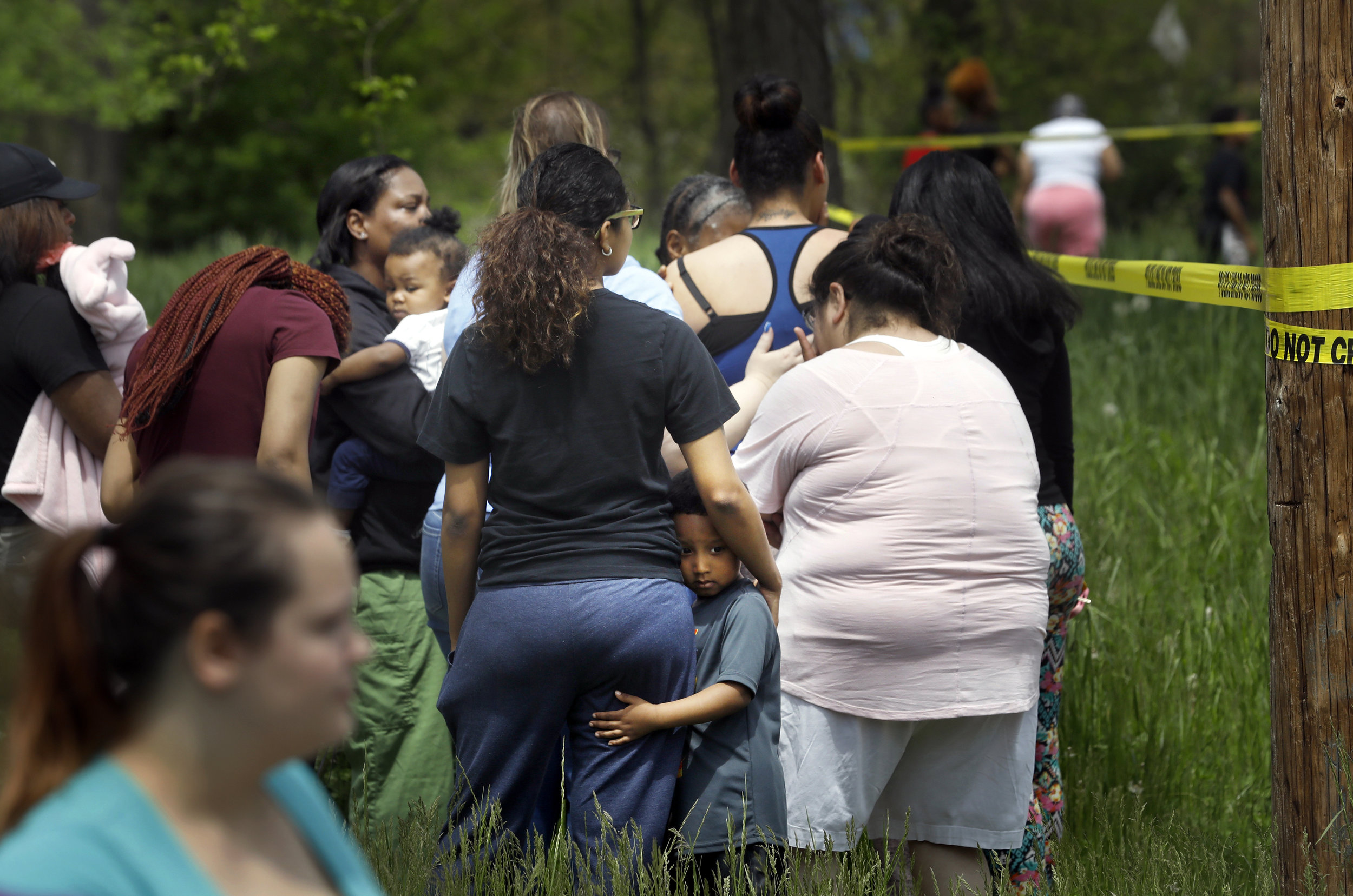 Torice Jackson, 3, clings to his mother Brooklyn Ruiz, as she talks with other mourners while Toledo Police investigate a shooting death that occurred in the early afternoon of May 17, 2018, on Highland Avenue near North Detroit Avenue in Toledo. Police dispatch confirmed officers responded at 12:42 p.m. for calls of a person shot. Ms. Ruiz said she knew the victim and his family well.