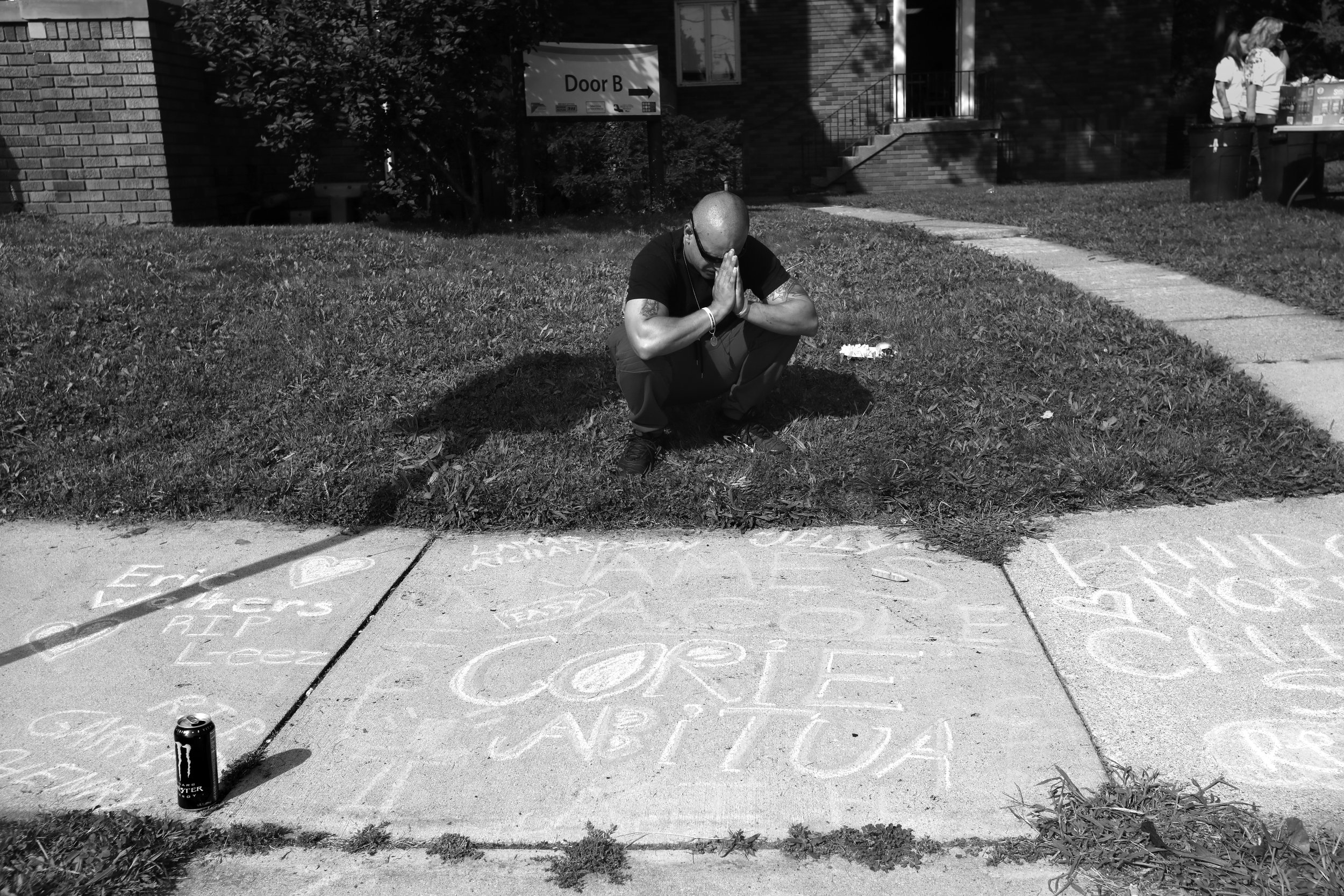  A man who agreed to be photographed prays near the chalked names of people he lost to opioid overdose during a remembrance event held at the Northwest Ohio Syringe Services, a harm reduction program that works with active drug users, in Toledo, Ohio