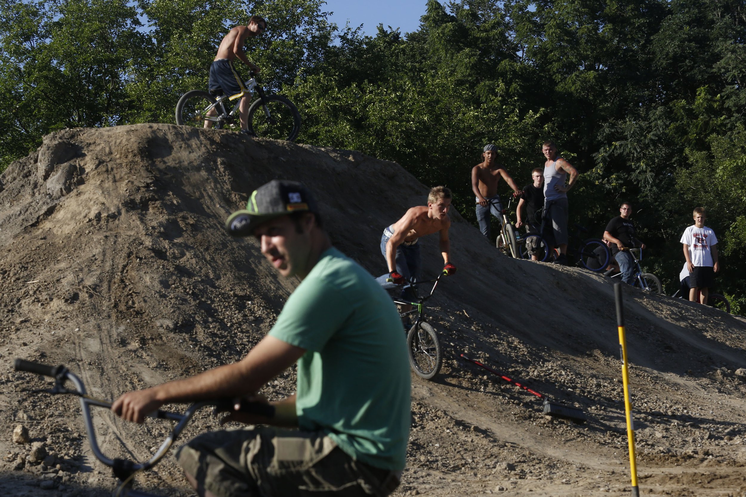  Alton Moran of Fostoria, center, flies down a mound as he and other riders work on creating a new jump park in a vacant area of West Toledo, Ohio, on July 24, 2013. The new BMX park I a grassroots effort by riders from around the region. 