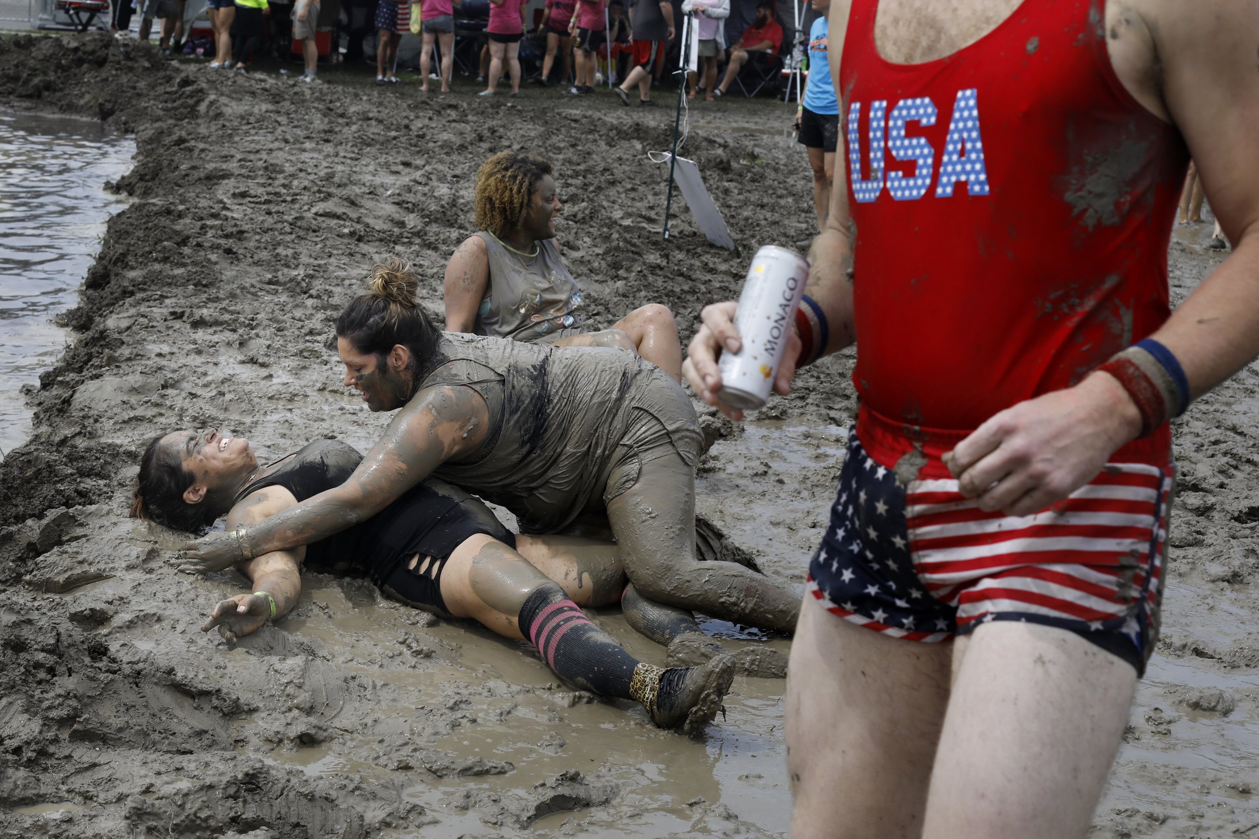  Jessica Black, center, slips as she tries to help a teammate up as they climb out of the submerged volleyball court in the seventh annual Mud Volleyball Tournament at the Lucas County Fairgrounds in Maumee, Ohio, on Aug. 25, 2018. The event was orga