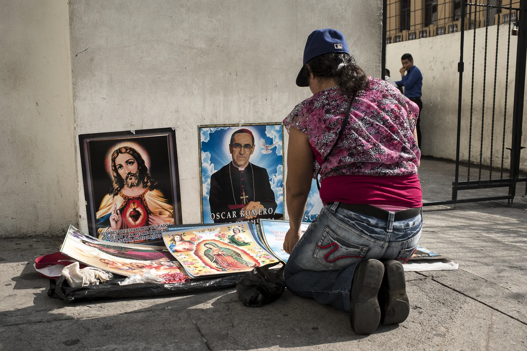 A Sunday morning at the time of the mass and near the Metropolitan Cathedral of the Holy Savior, a woman is selling some poster of the Christ and Monsignor Romero, archbishop of San Salvador taht was killed by the military and the beginning of the 1980. He still stays a popular and loved figure of the contemporary Salvador.