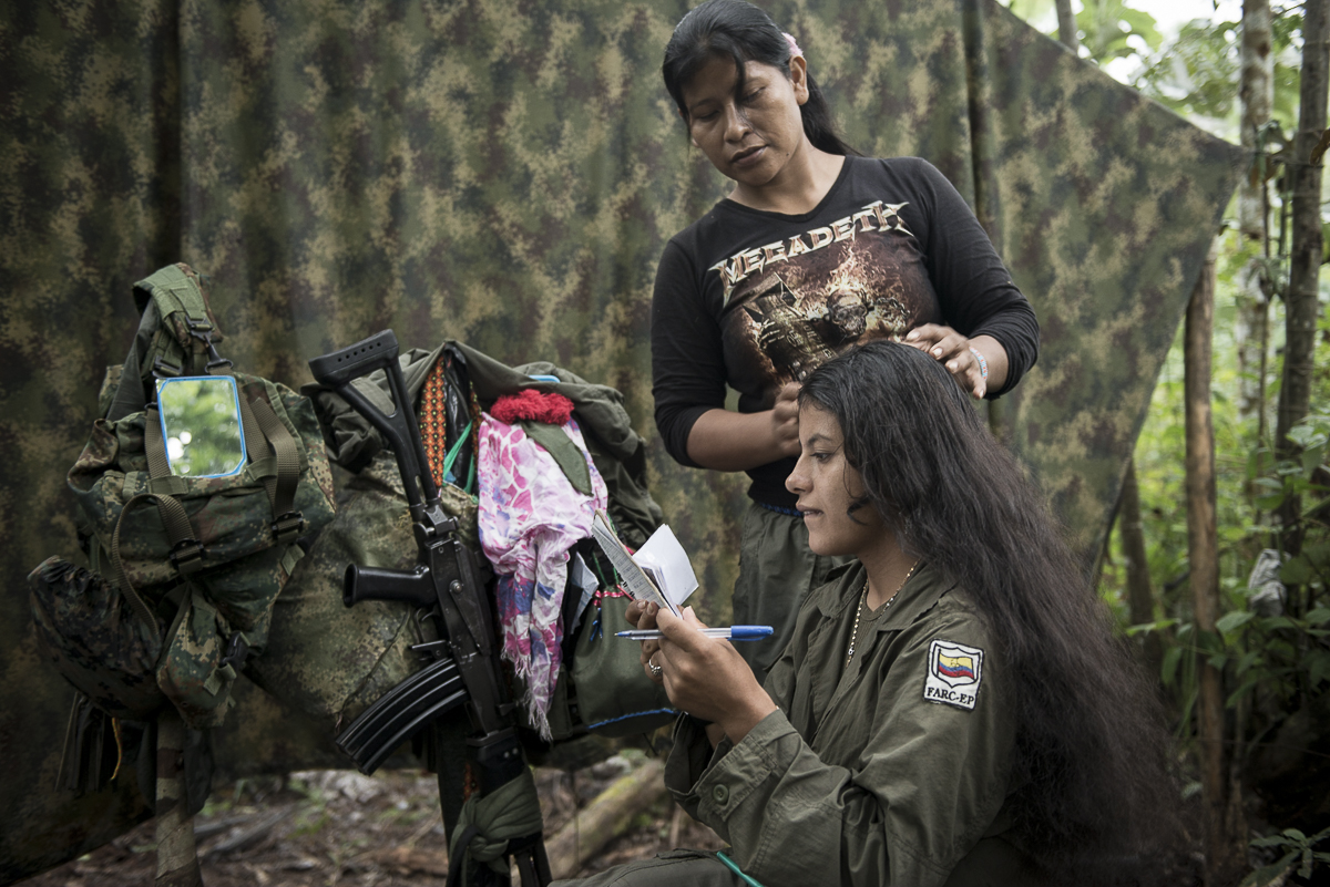 A guerrillera reviews the encoding of the messages she will send by radio to other groups or to the command, Her comrade begins to plait her hair. (May 11, 2015. South Caquetá)