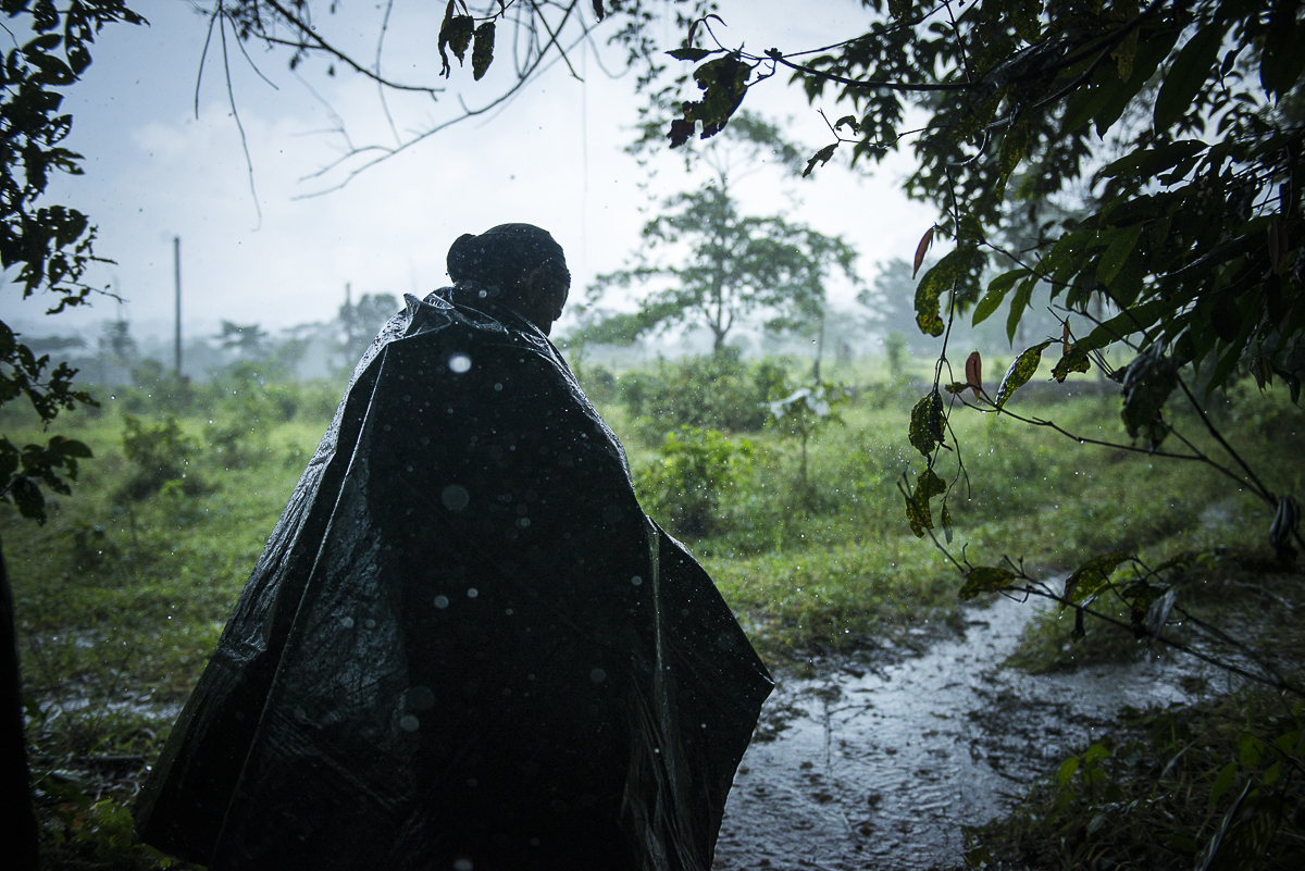 A rainfall comes down on the camp. A guerrillero goes to a tent protecting himself with a plastic coak. The region is a gateway to the Amazon and its jungle. The rain is really heavy most of the time. (June 28, 2016, South Caquetá)