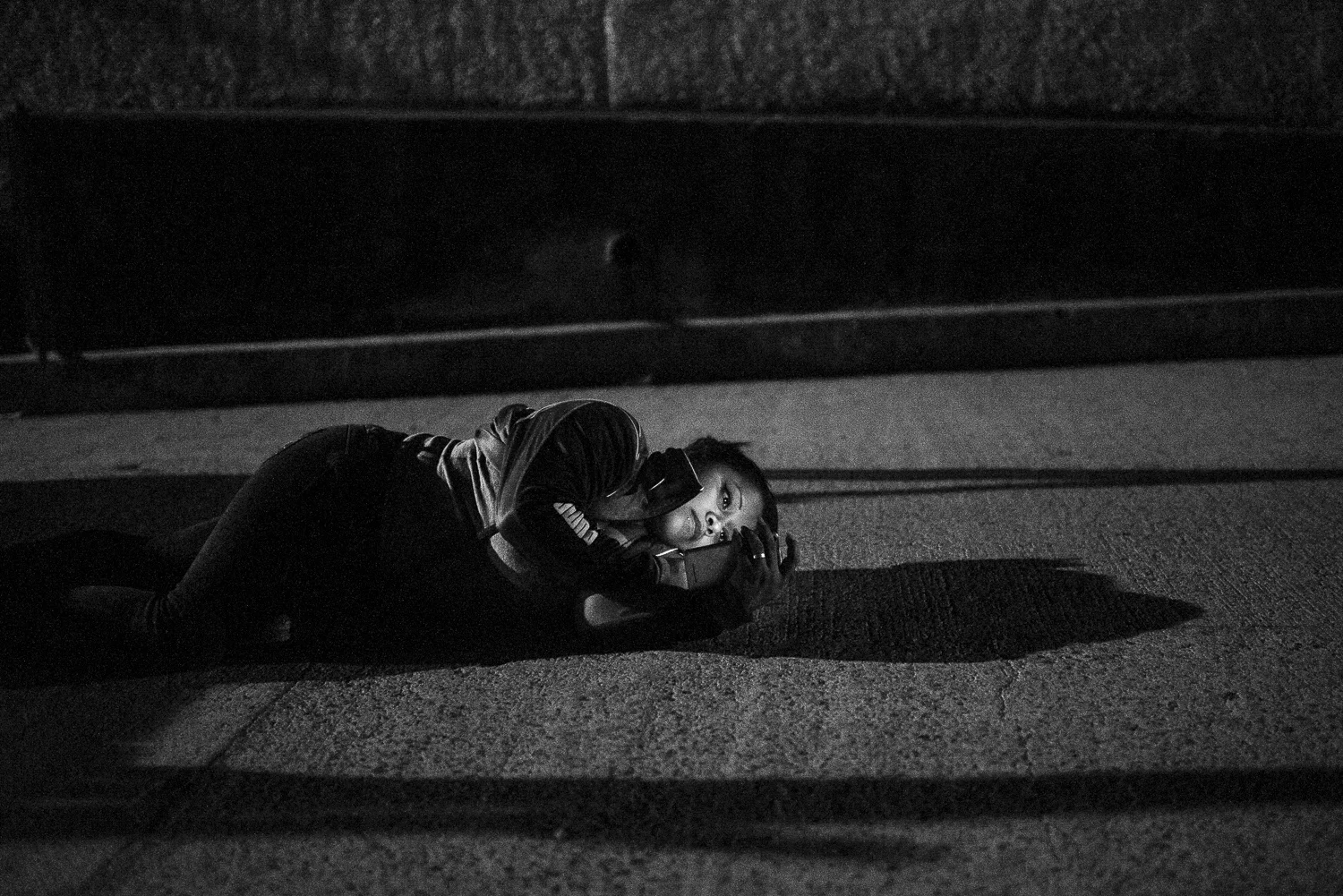Just before to start the trip to La Gotera jail, Maira is on the ground, consulting her phone. Her husband is detained for his past activities as gang member. He is now an evangelical. Maira couldn't communicate with her husband since the implementation of the restrictive mesuresin 2016. Maira is part of New Creation church, Angel' ministry. (April 18, 2018) Credit: Nadège Mazars / Hans Lucas studio