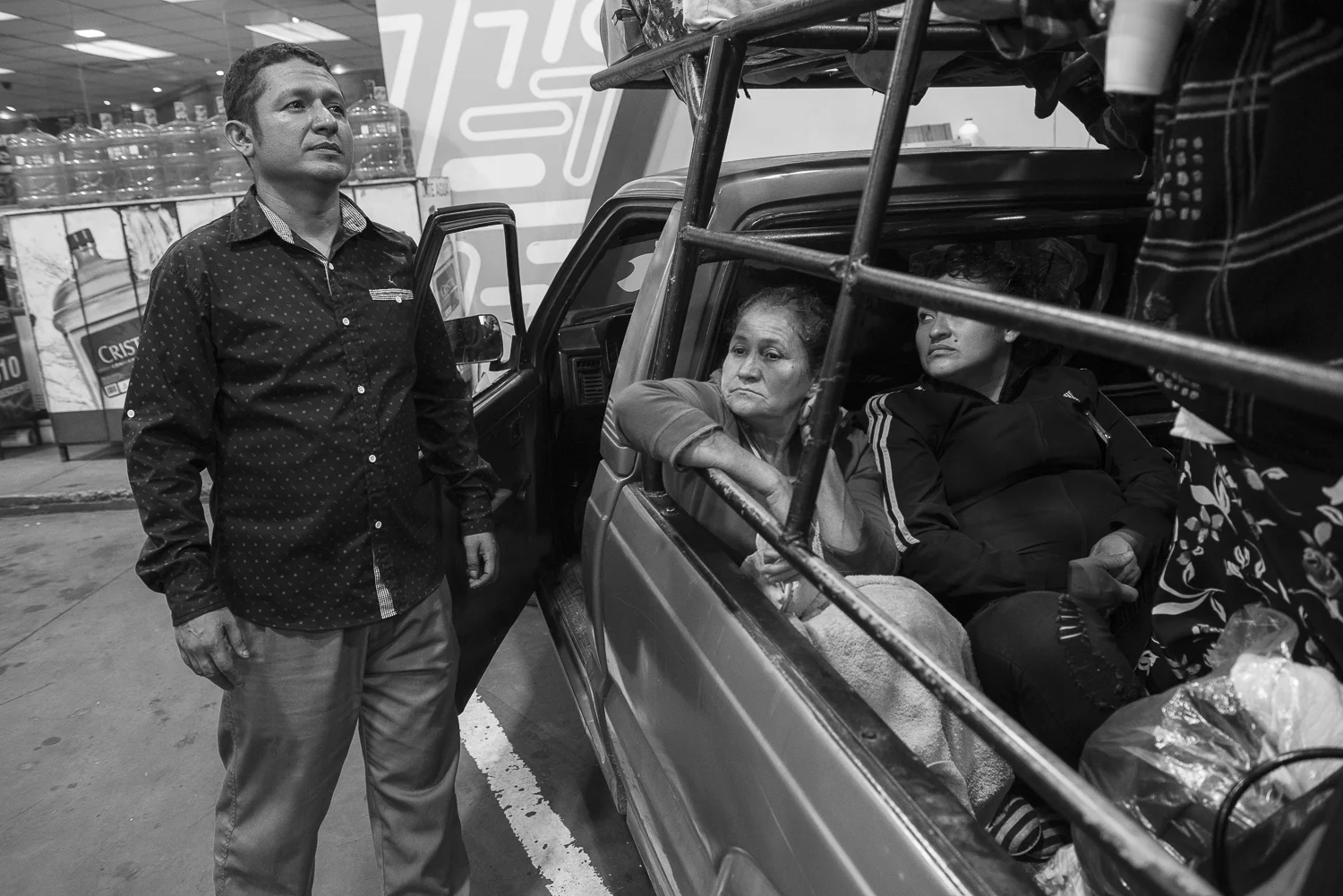 Angel is looking at the passengers on the back of the pick-up. He organized a trip to San Francisco de la Gotera jail of twelve women, wife or mother of a detained, at 5 hours of San Salvador. The purpose is to bring some packages of food or first need products to the detained. Since almost two years the jail is under restrictive measures that prohibit any contact with outside. In late April, the measures started to be more flexible. (April 19, 2018) Credit: Nadège Mazars / Hans Lucas studio