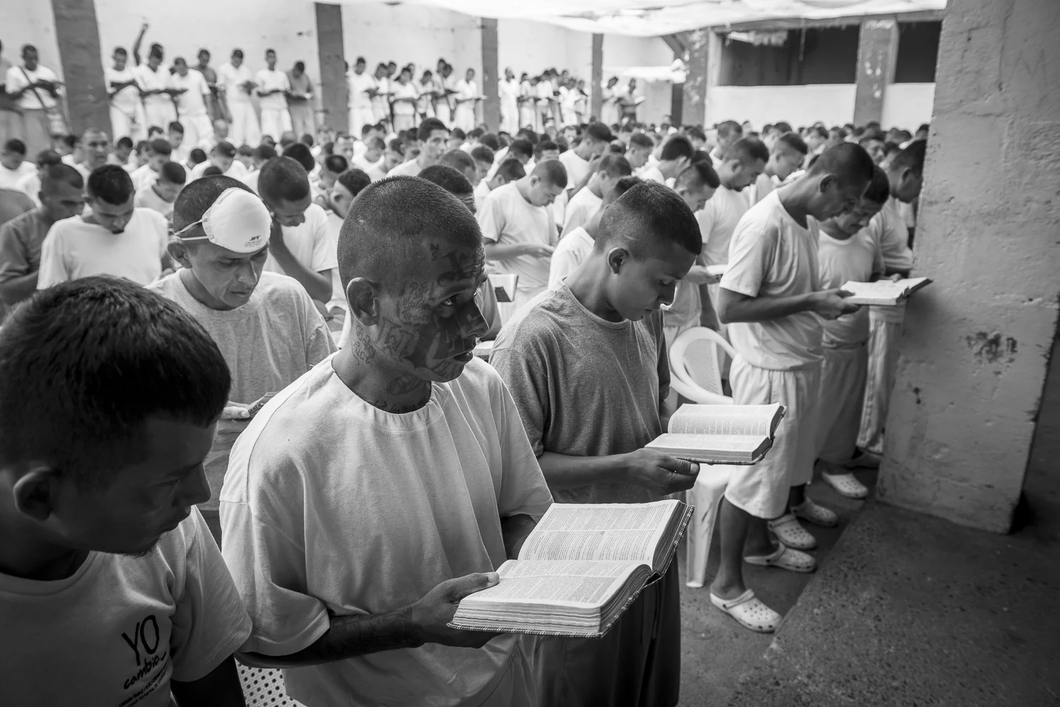 At the time of a worship, a prisoner with tattoo on his face is listening to the pastor. This part of the jail is recently converted to Christianity. (San Francisco de Gotera, El Salvador, April 19, 2018) Credit: Nadège Mazars / Hans Lucas studio
