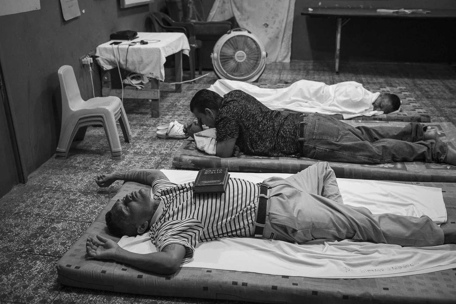 The former gang members are sleeping in the same room where they make the bread. The Eben Ezer church has limited resources. Saul Antonio is sleeping with his bible on the abdomen. He was released few days ago. (San Salvador, El Salvador, April 16, 2018) Credit: Nadège Mazars / Hans Lucas studio
