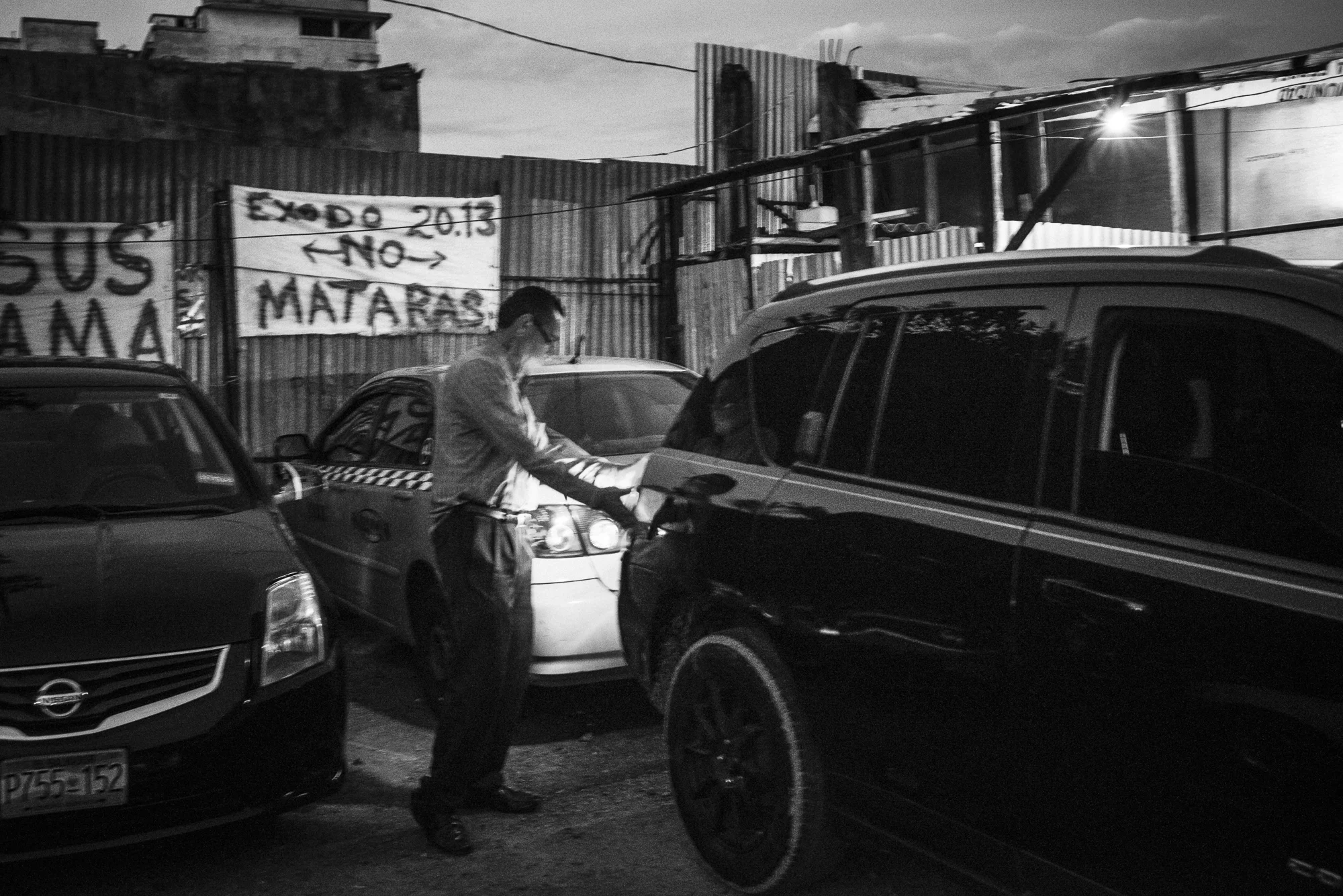 Edwin is helping a car to park in the place where he lives and where is his church. On the wall, a banner says: “Exodus 20:13. You shall not murder”. He explains he survives only thanks to some donations and with the few income to manage with two others “brothers” the car park area. He dedicates the rest of his time to God, beginning the day praying at one o’clock in the morning.