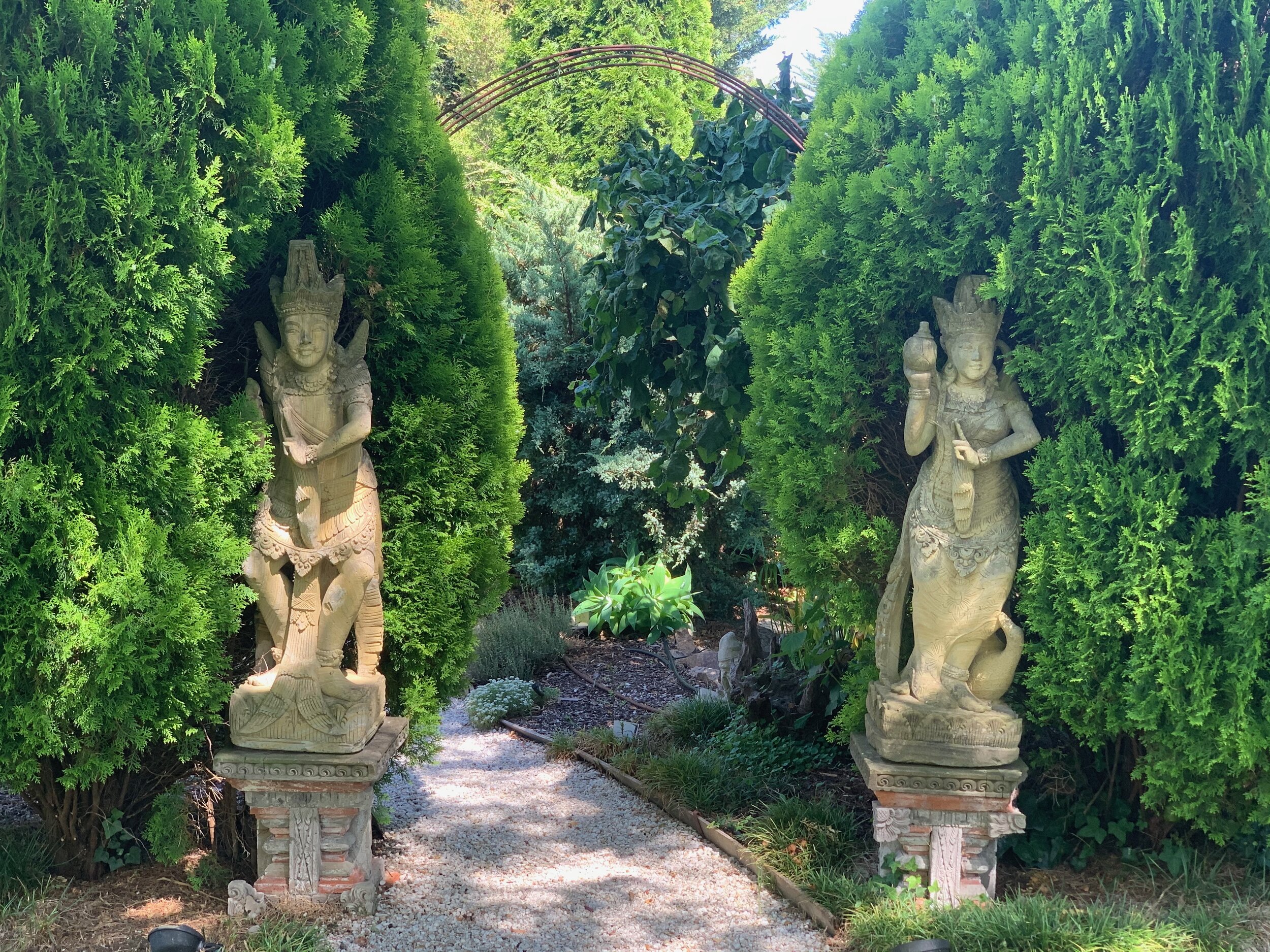 Down the garden path - antique statues flank one of the may entries to secret outdoor rooms at Leonets.