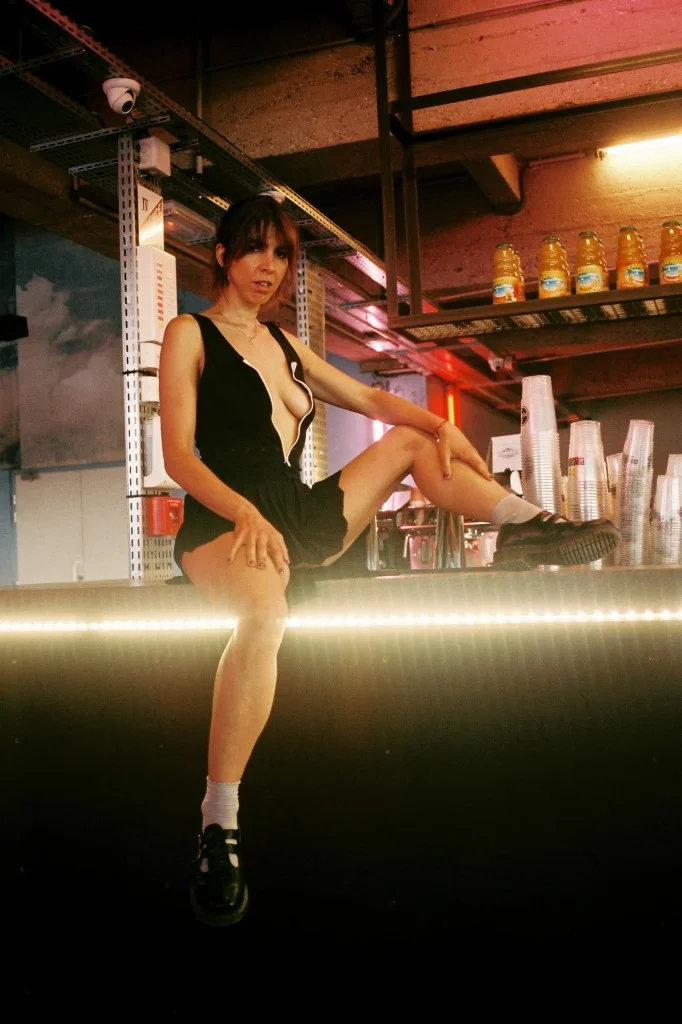  Hala Moawad (Stylist) wears AMERICAN APPAREL bodysuit and socks, MUGLER skirt, and DR. MARTENS shoes. 