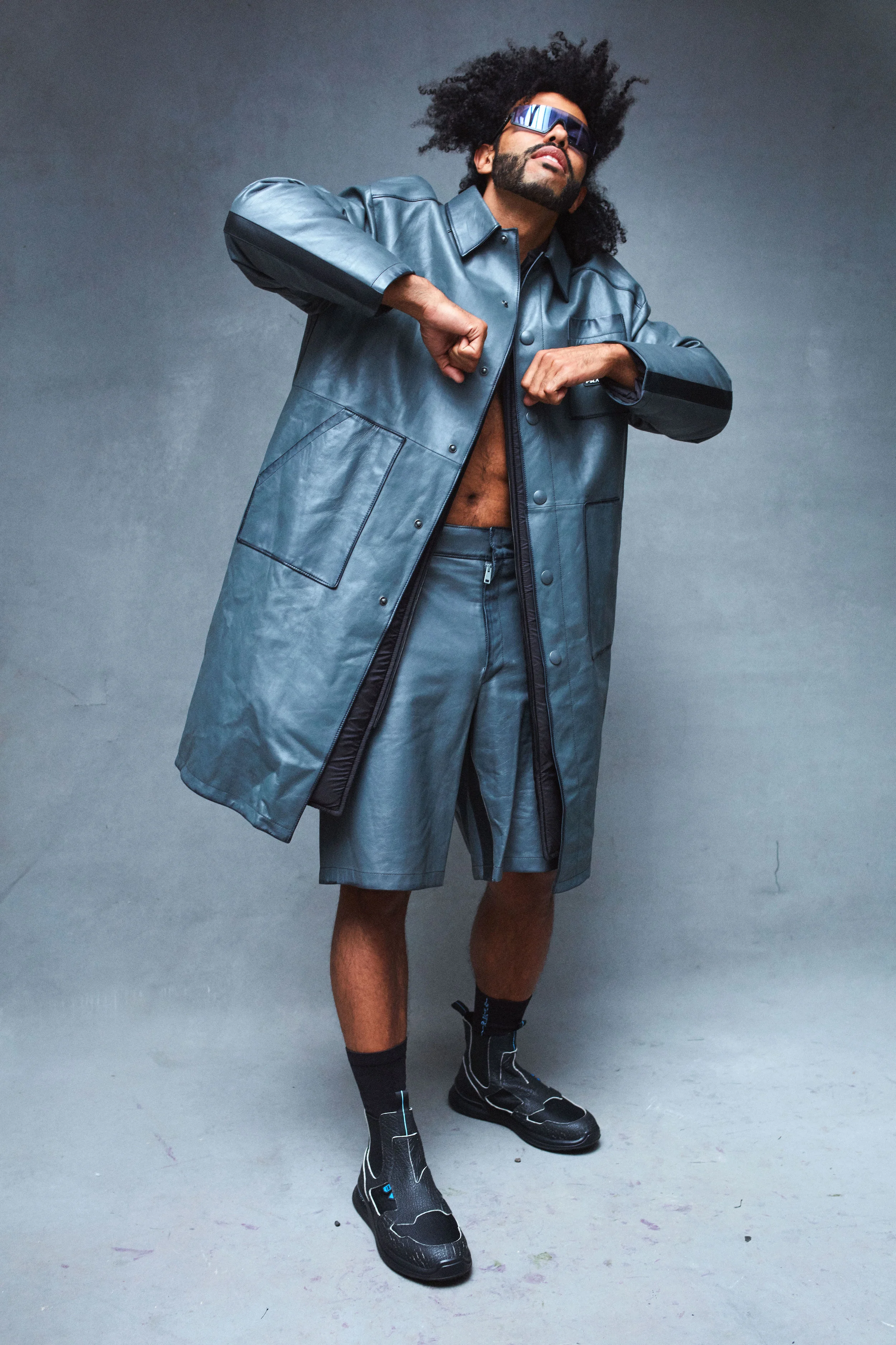 PRADA coat, shorts, and shoes and WESTWARD LEANING sunglasses.