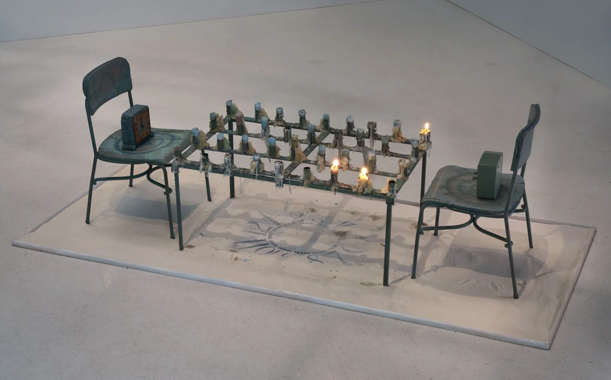 “The Game of Time,” (2013). Tableau: Child’s chair with orange face clock, Metal table with candles, Rectangular clock face in sand, and Child’s chair with green clock. 68 x 30 x 20 inches. Courtesy the Artist and Roberts & Tilton, Culver City. Photo: Robert Wedemeyer.
