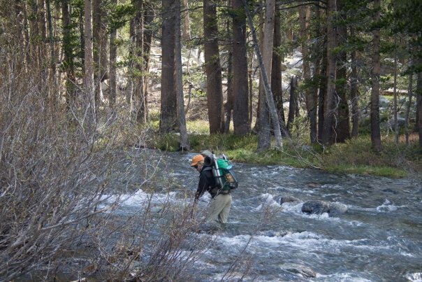 Stream crossing with ultralight pack, orange hat and re-purposed stick as assistance device.