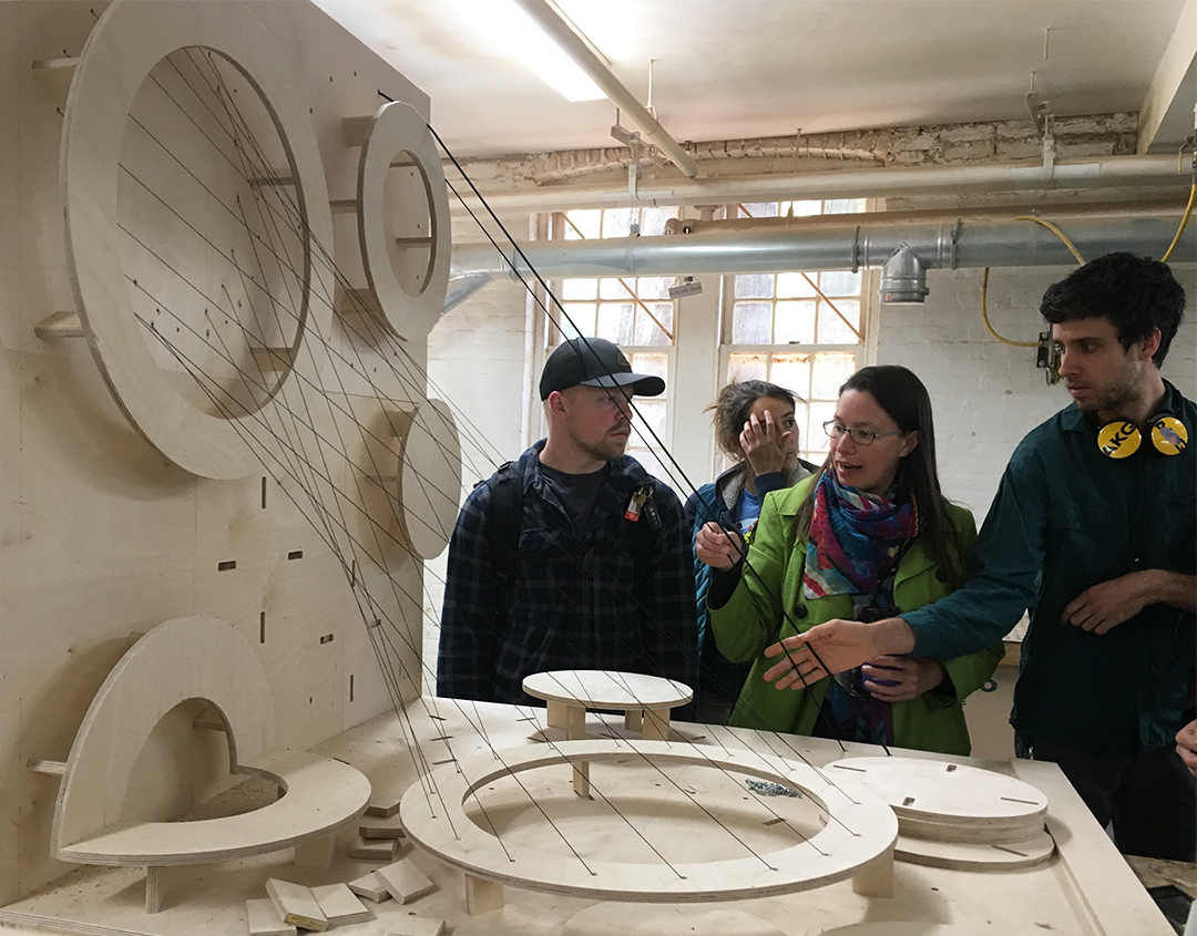 The team assessing a scale model of the piece.
