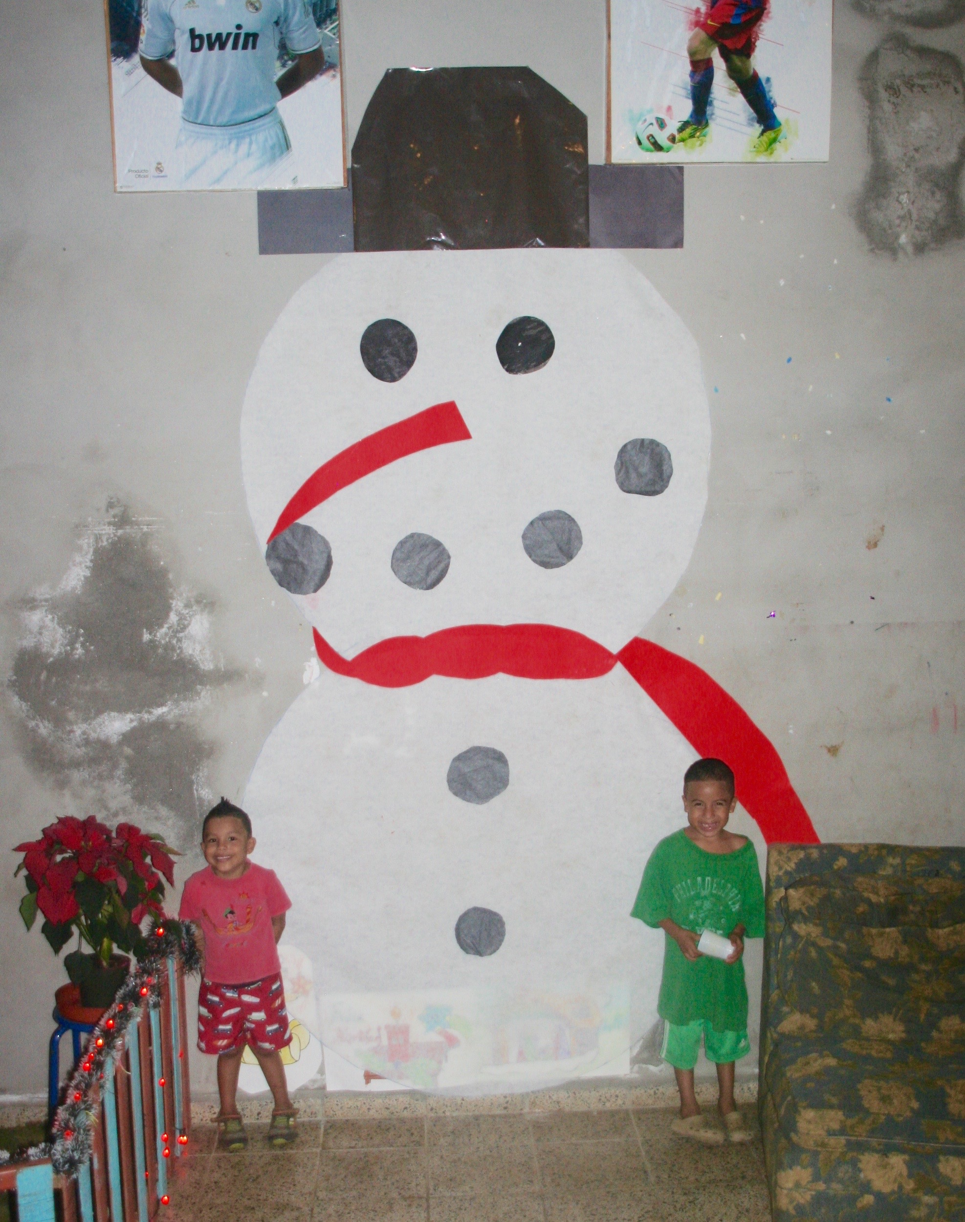 Edwin and friend posing in front of a giant snowman they helped make on the wall of their dorm during Christmas.