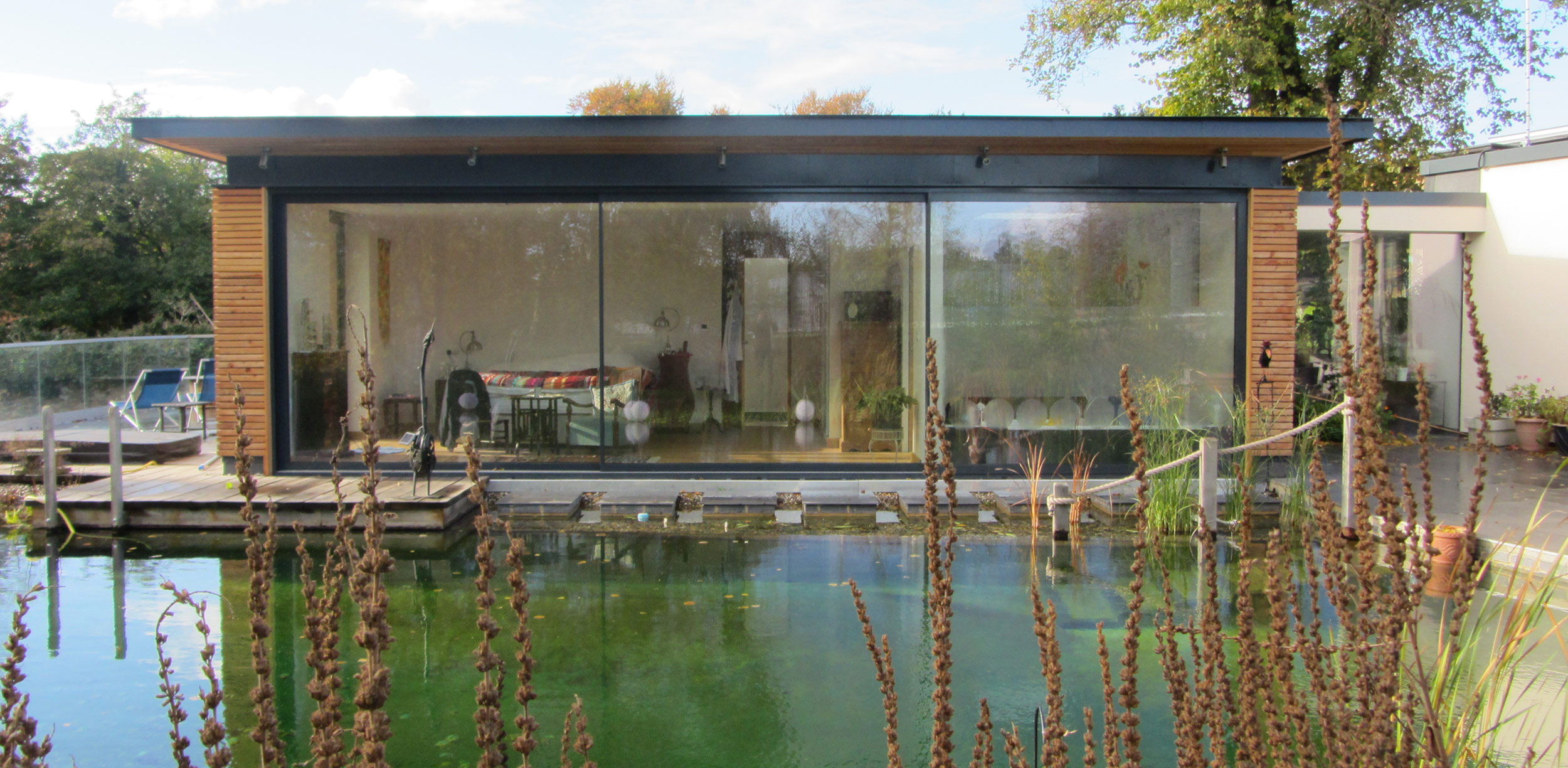 Bedroom block with larch cladding as viewed from across the natural swimming pond
