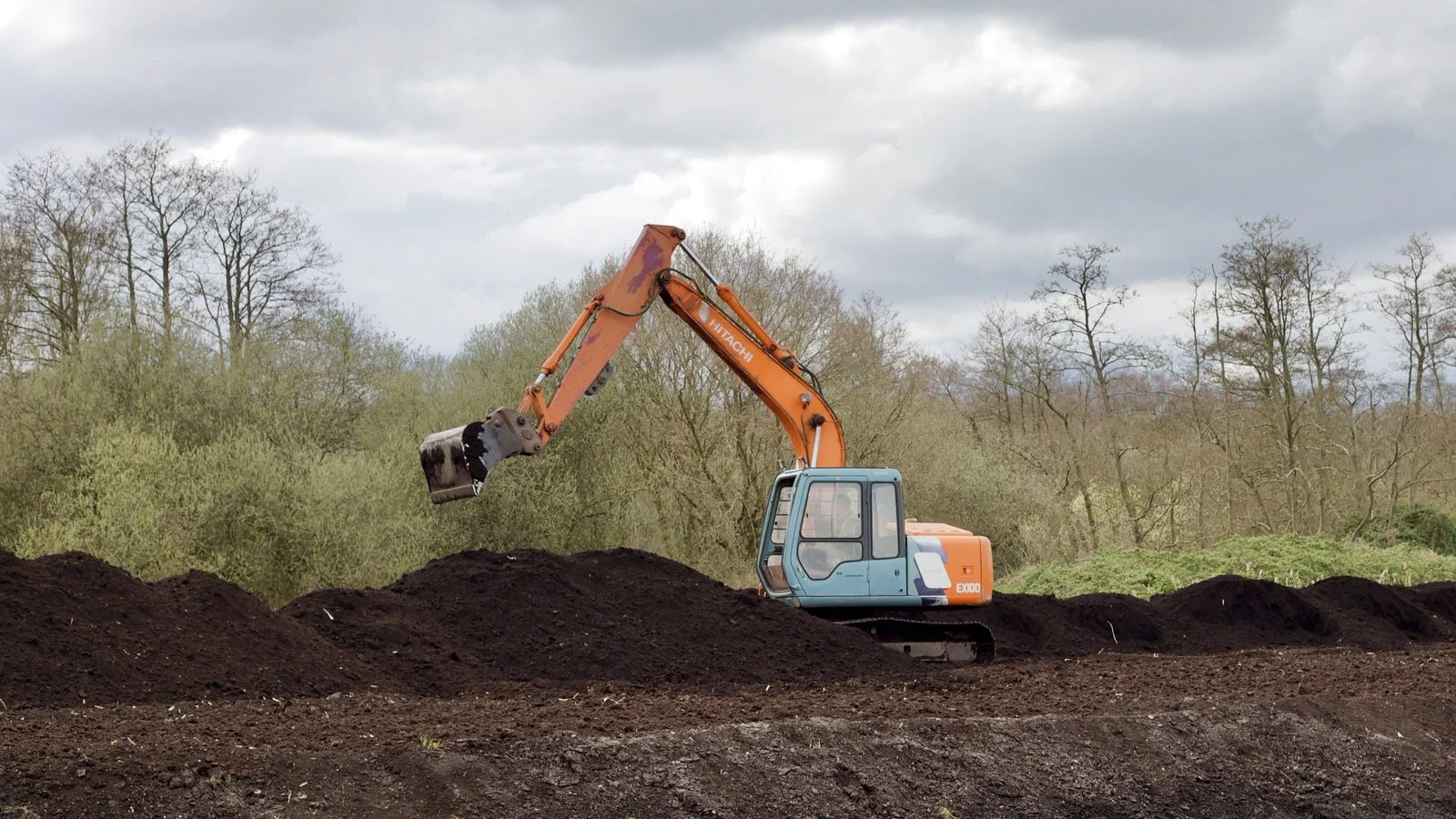 a digger lifts out peat from marshland