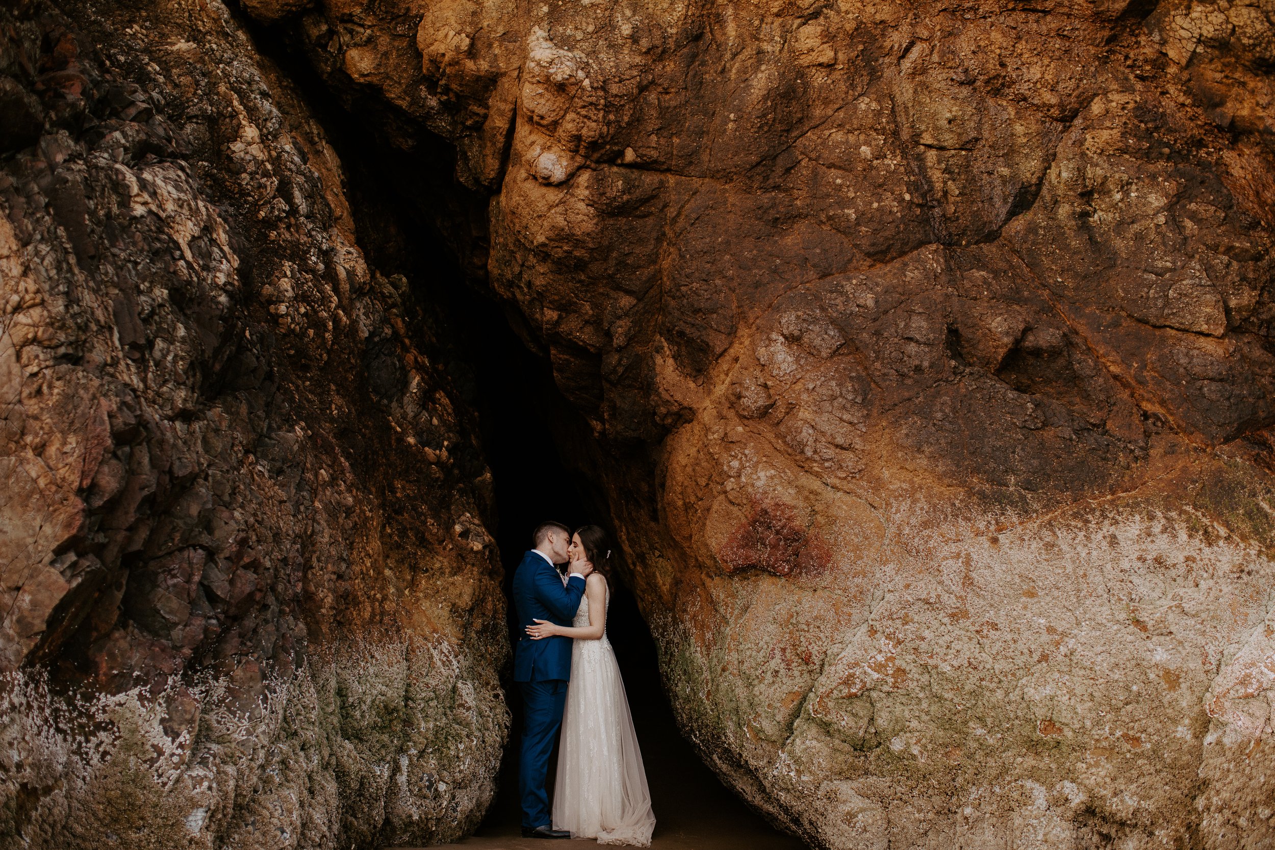 Bride and groom kissing in a cave at Hug Point