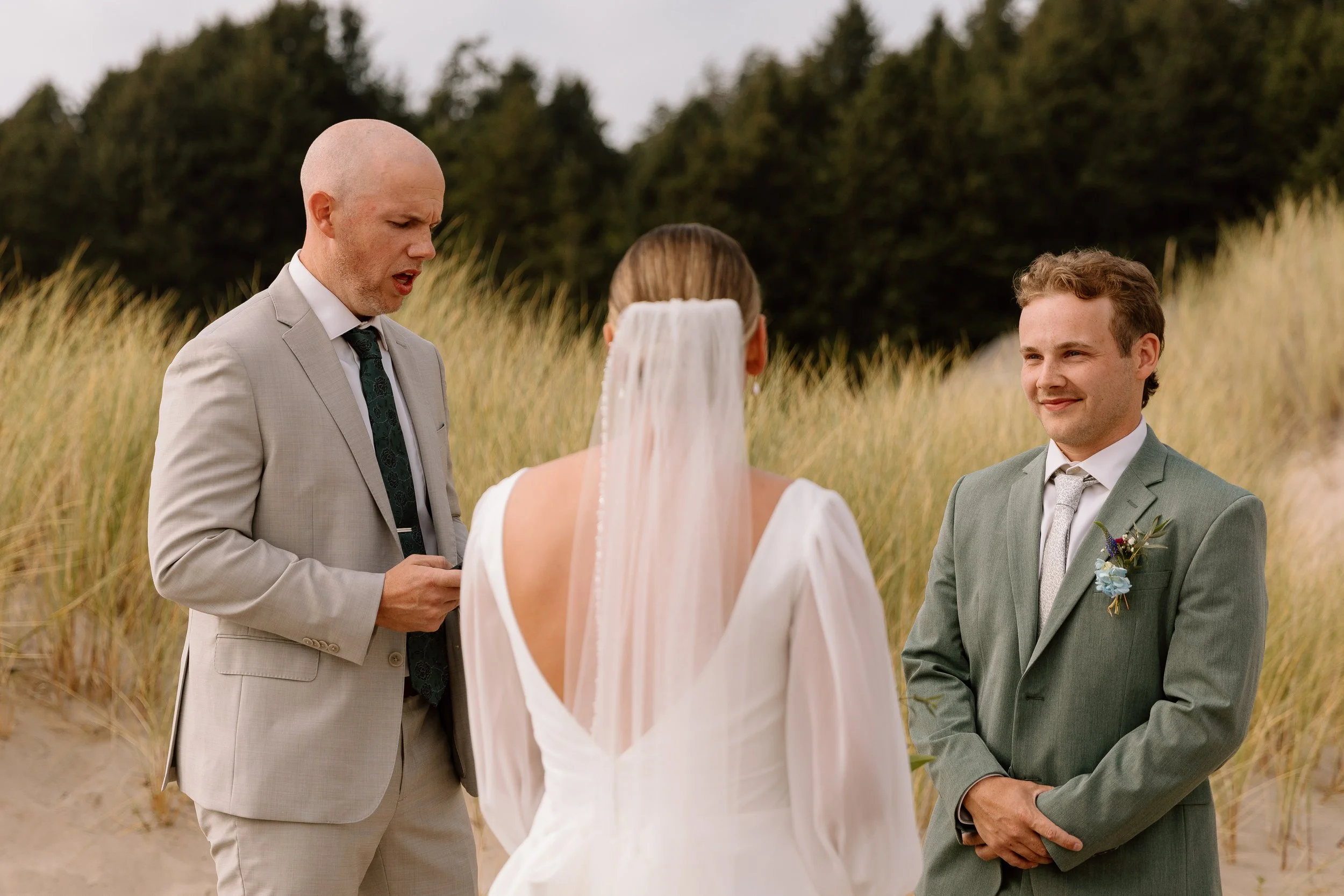 Groom smiling at his bride during his ceremony at cannon beach