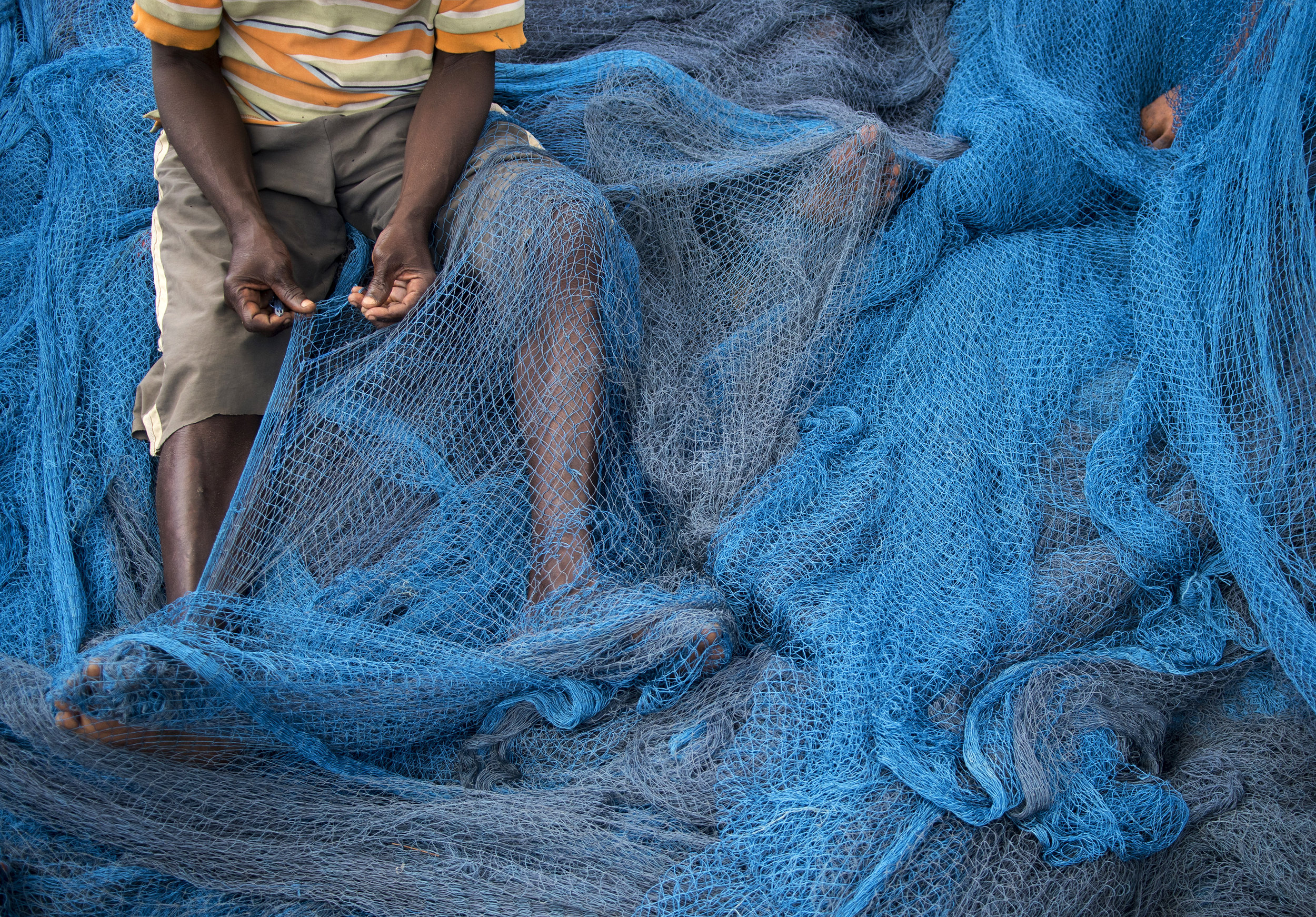  Hundreds of feet of netting must be carefully examined and repaired by hand after each fishing expedition. Debris along the ocean floor or fish forcing their way through weak points create holes that must be patched before the next trip out. 