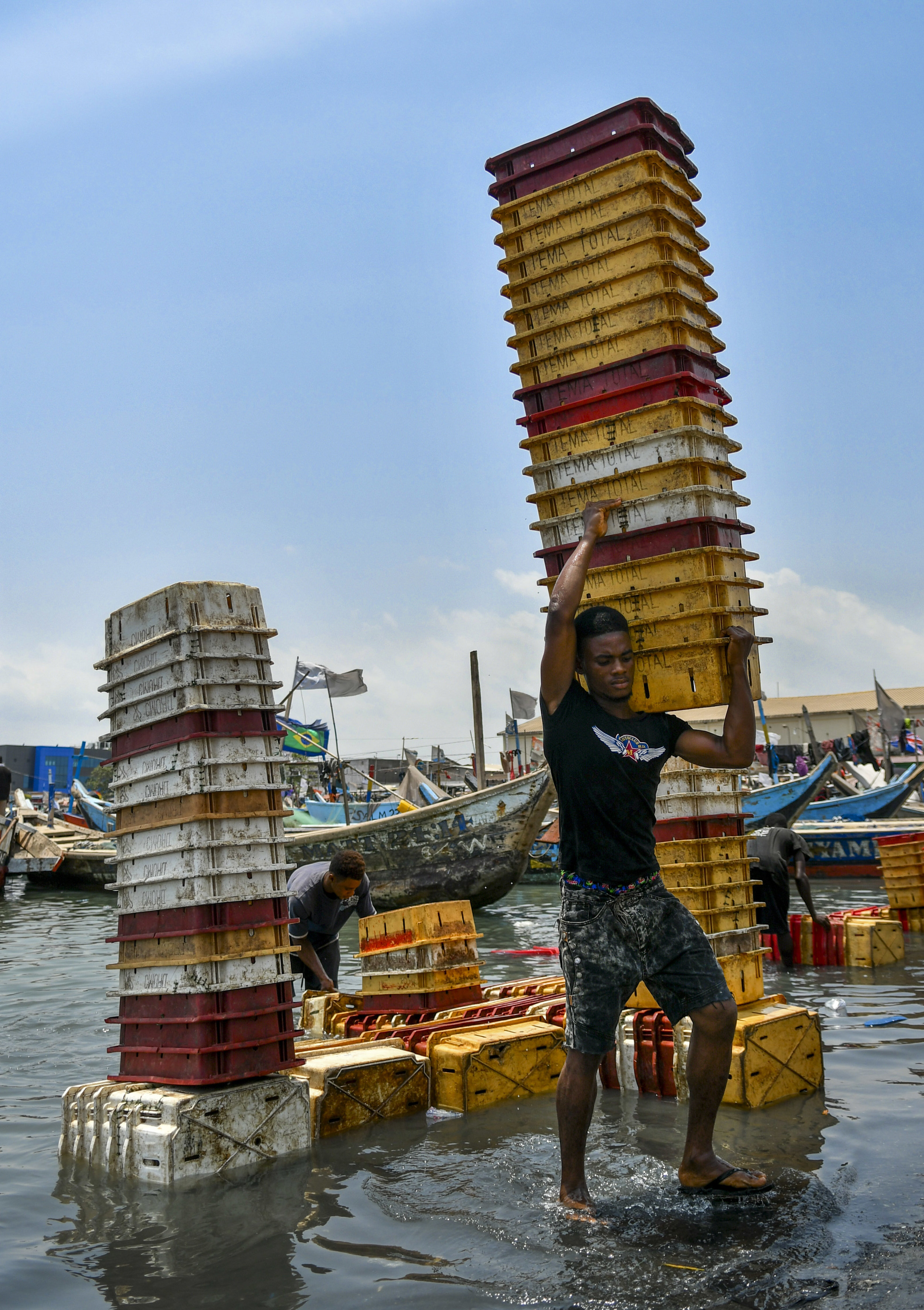  Young men clean plastic containers that carry fish from the boats, measure fish quantities or are used to display fish for market. Hundreds of these plastic containers line the shoreline of Tema Port, the largest marina in Ghana. 