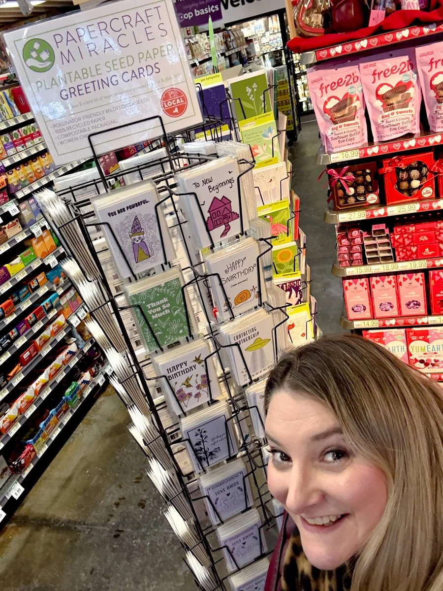 White woman in front of a spinning rack of greeting cards
