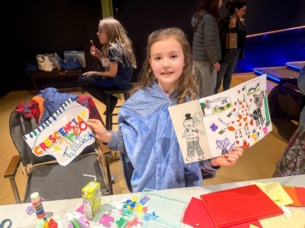 White girl holding handmade art at event childcare area