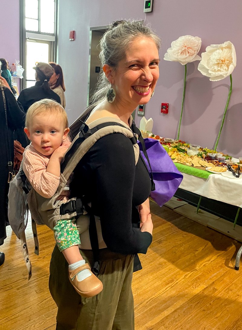 White mom smiling with a baby in a carrier