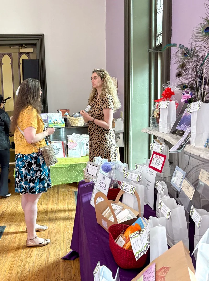 White women talking at an art event basket raffle table