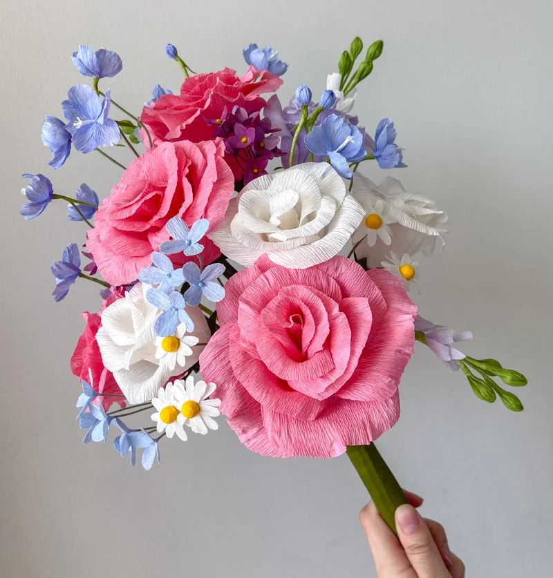 Handmade paper flower bouquet with pink and white roses, blue flowers, and white daisies