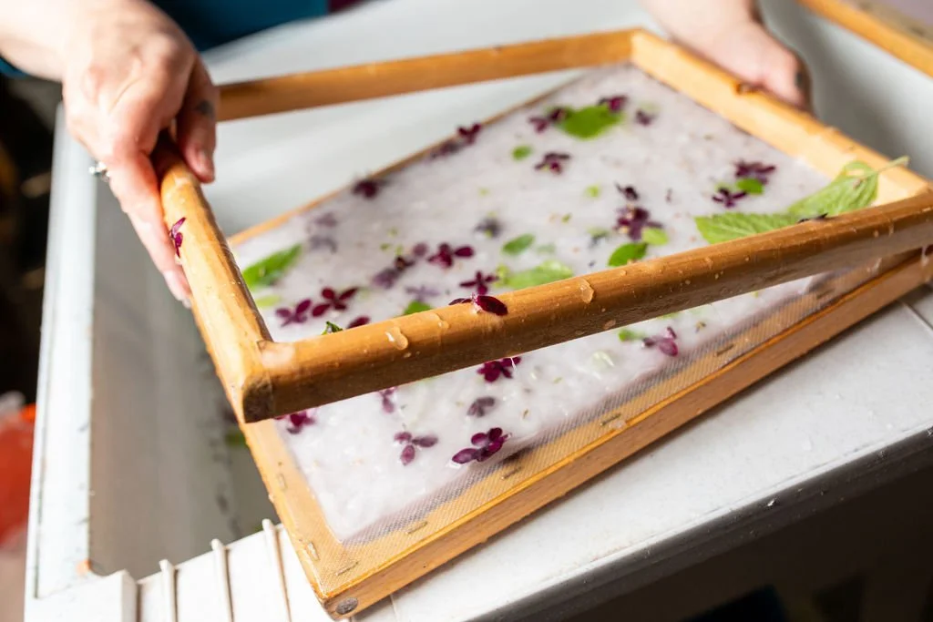 Handmade paper being created with flower petals and leaves