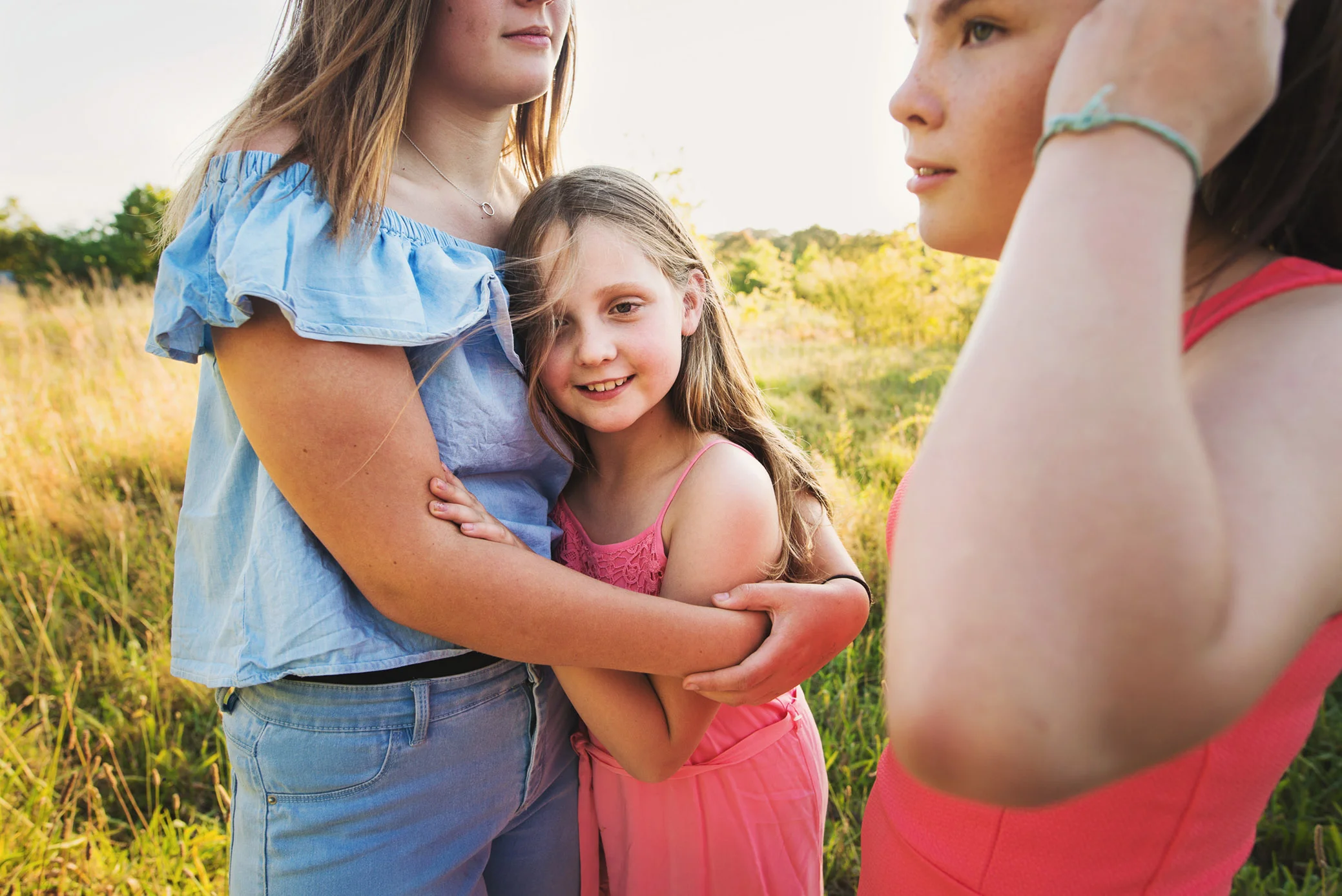 three sisters hugging at sunset