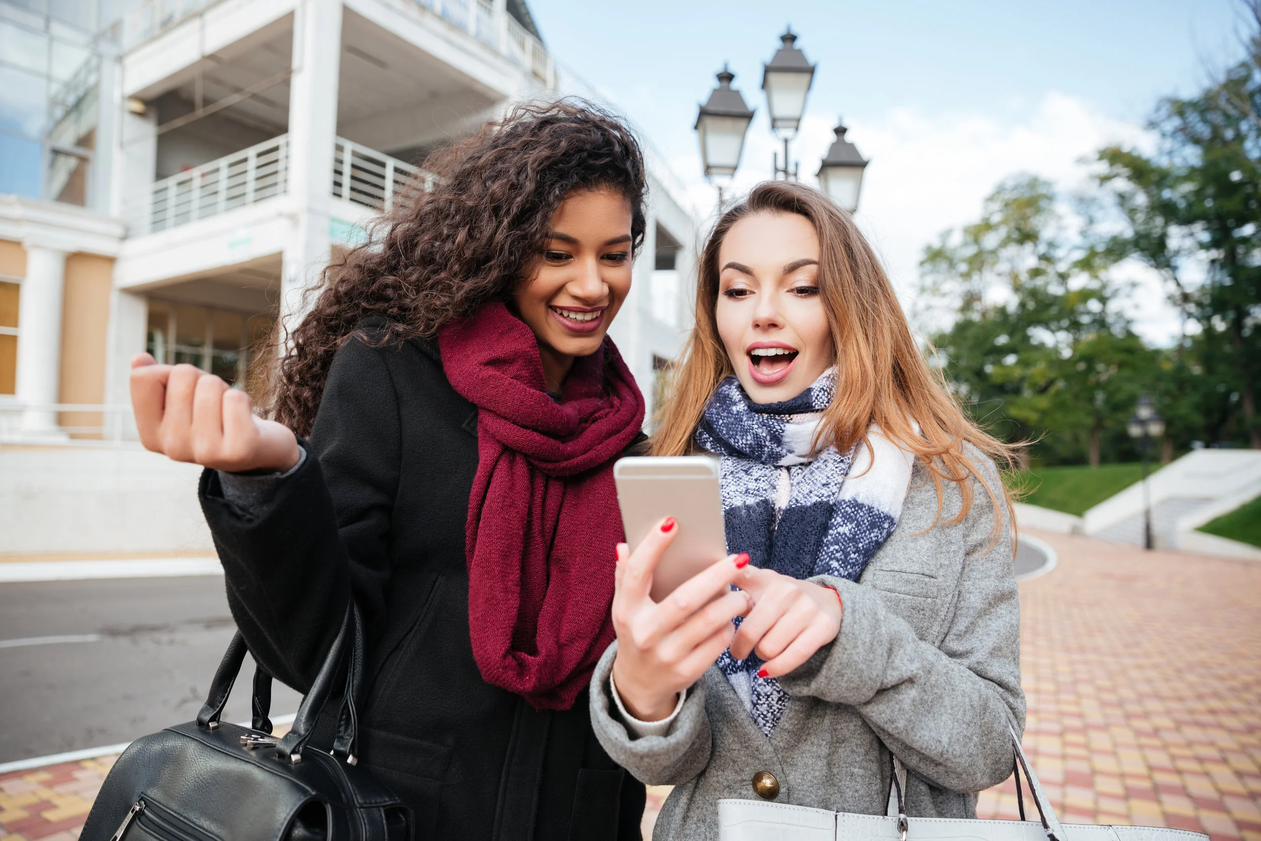 graphicstock-euphoric-friends-watching-videos-on-a-smartphone-and-pointing-at-screen-surprised-caucasian-girl-wearing-scarf-in-a-cage-print-african-lady-wearing-burgundy-scarf_rOfaSaKUhg.jpg