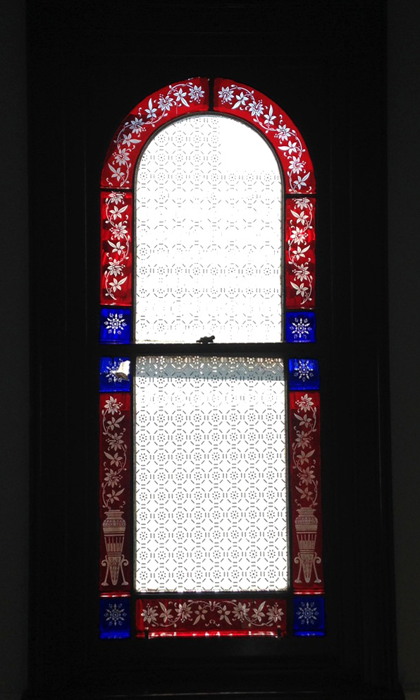 arched window with red sandblasted glass and blue glass starbursts