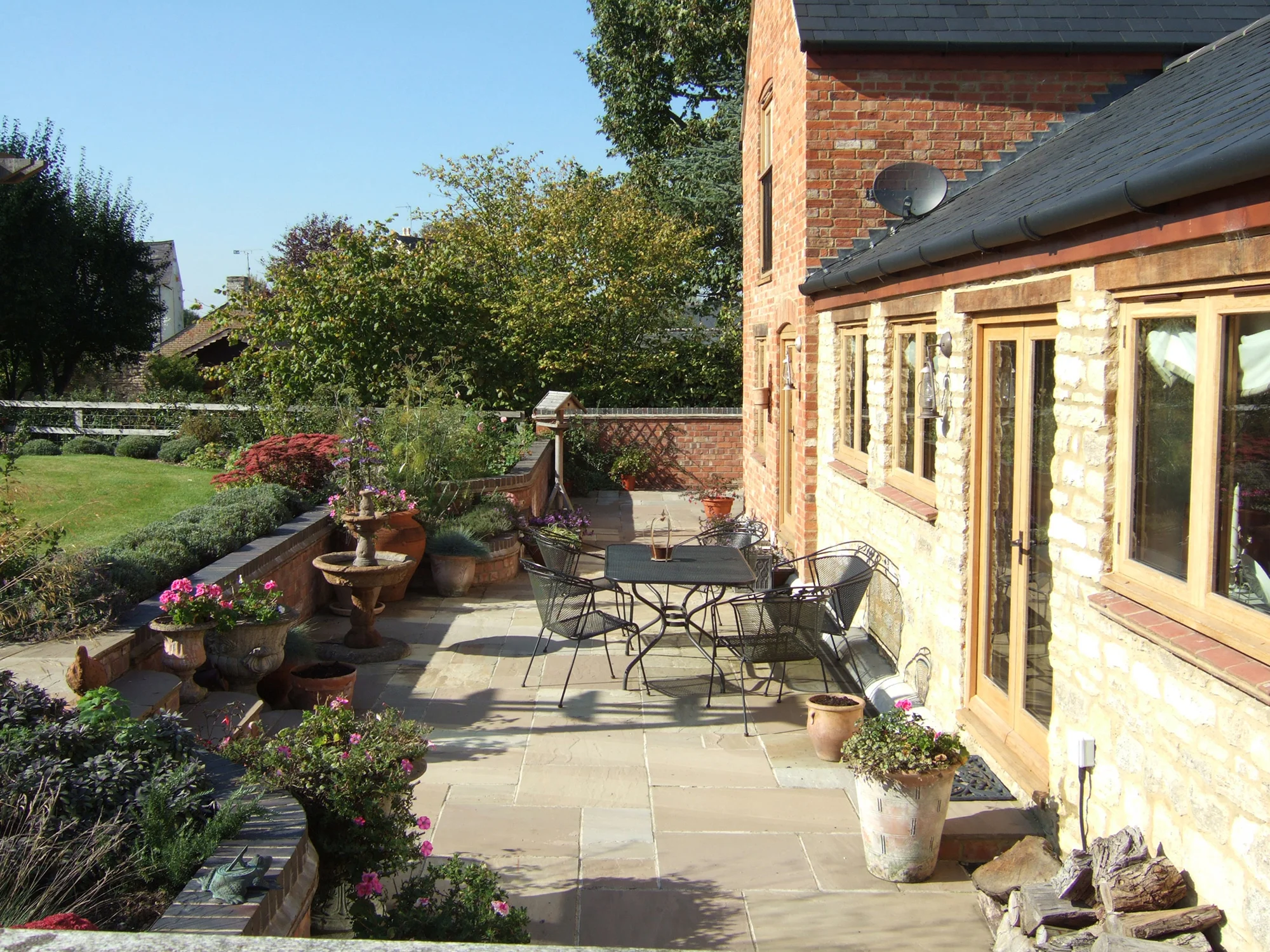 Patio area outside of a barn conversion with Kettler garden furniture and lots of flowering pots