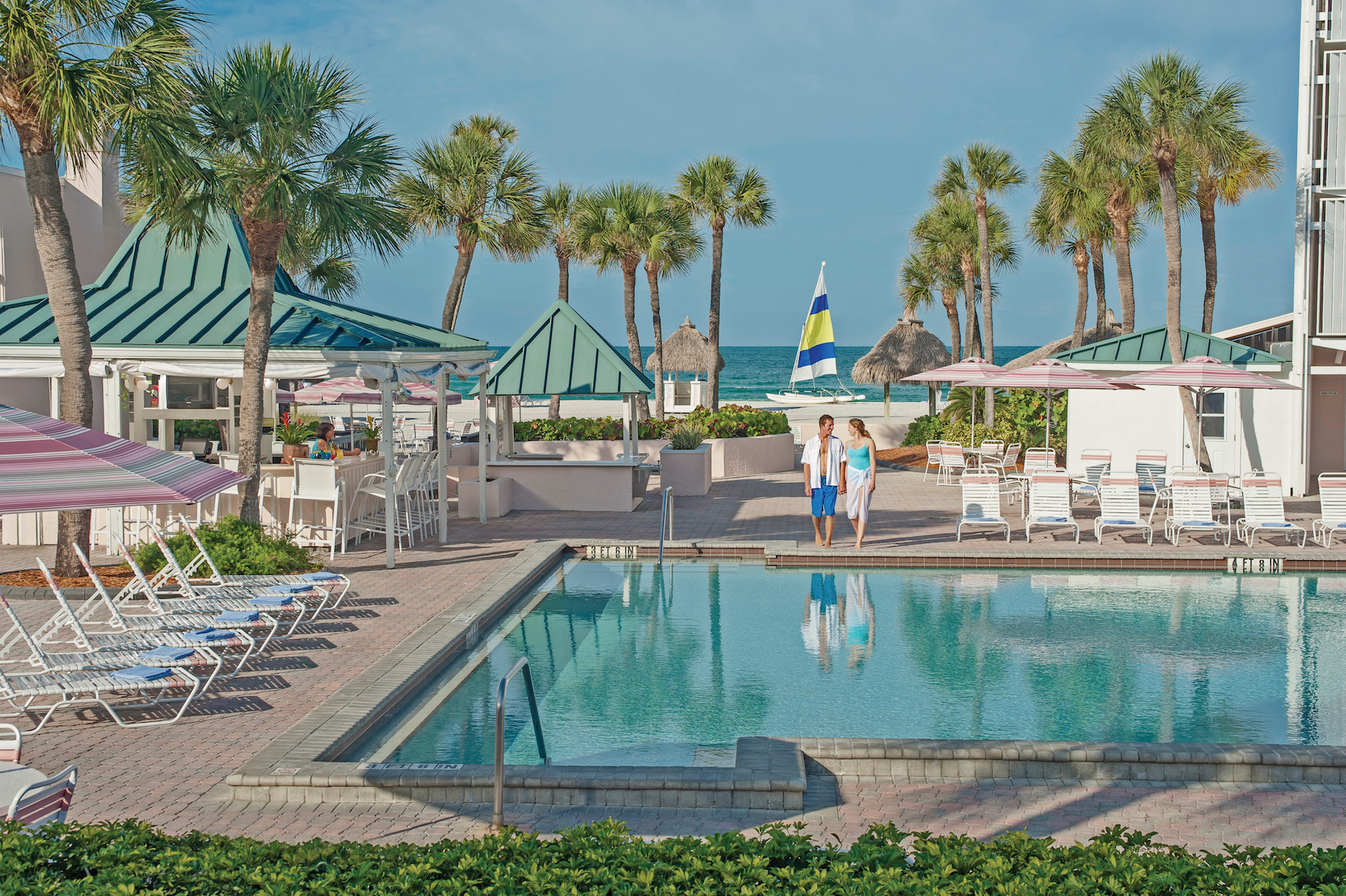 couple holding hands in front of pool at Sandcastle Resort at Lido Beach.jpg