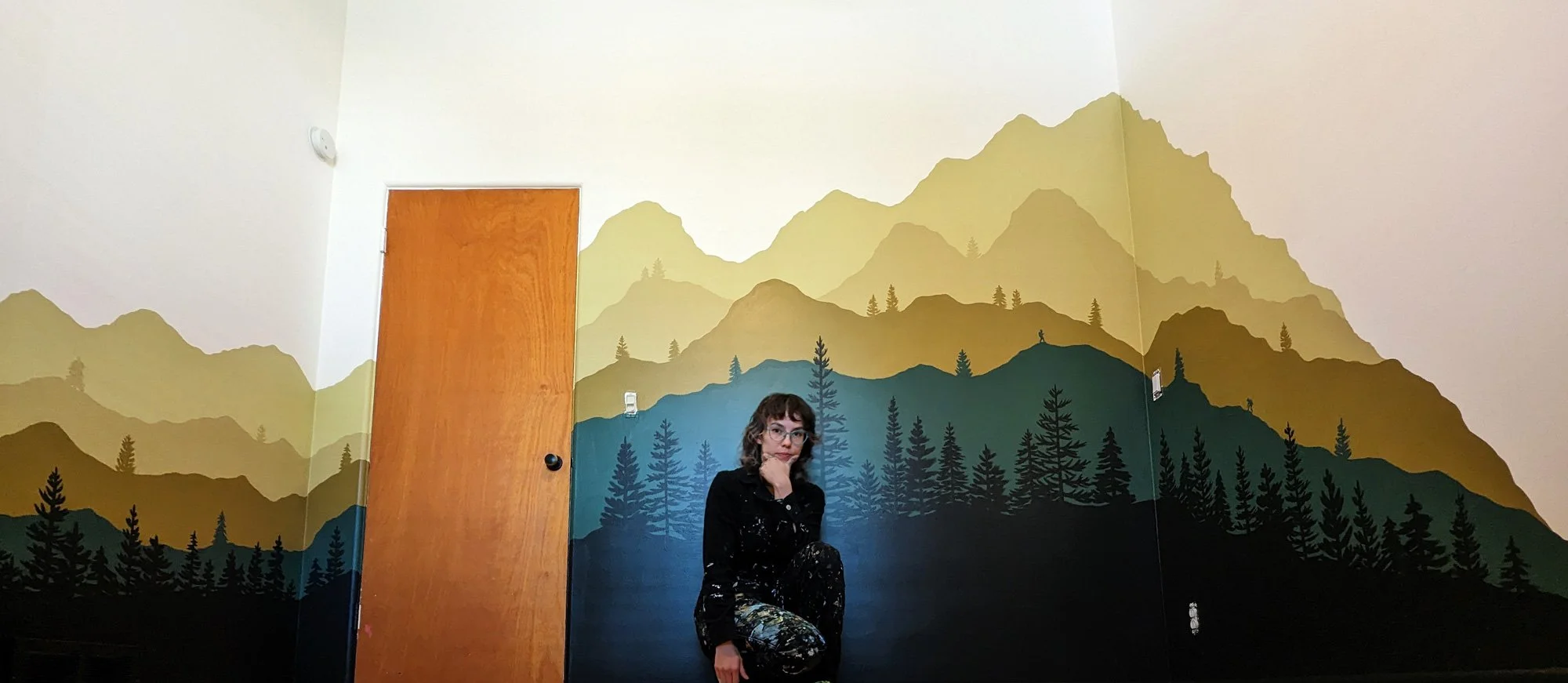 Mountain Bedroom mural painted in michigan with mountain layers and pine trees in green and gold.