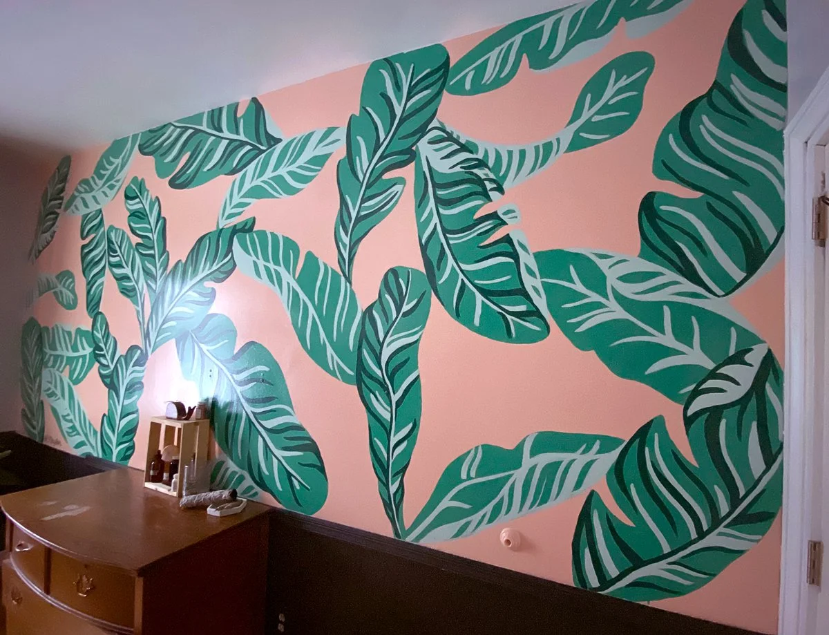 Tropical bathroom mural in Marquette Michigan with banana leaves on pink