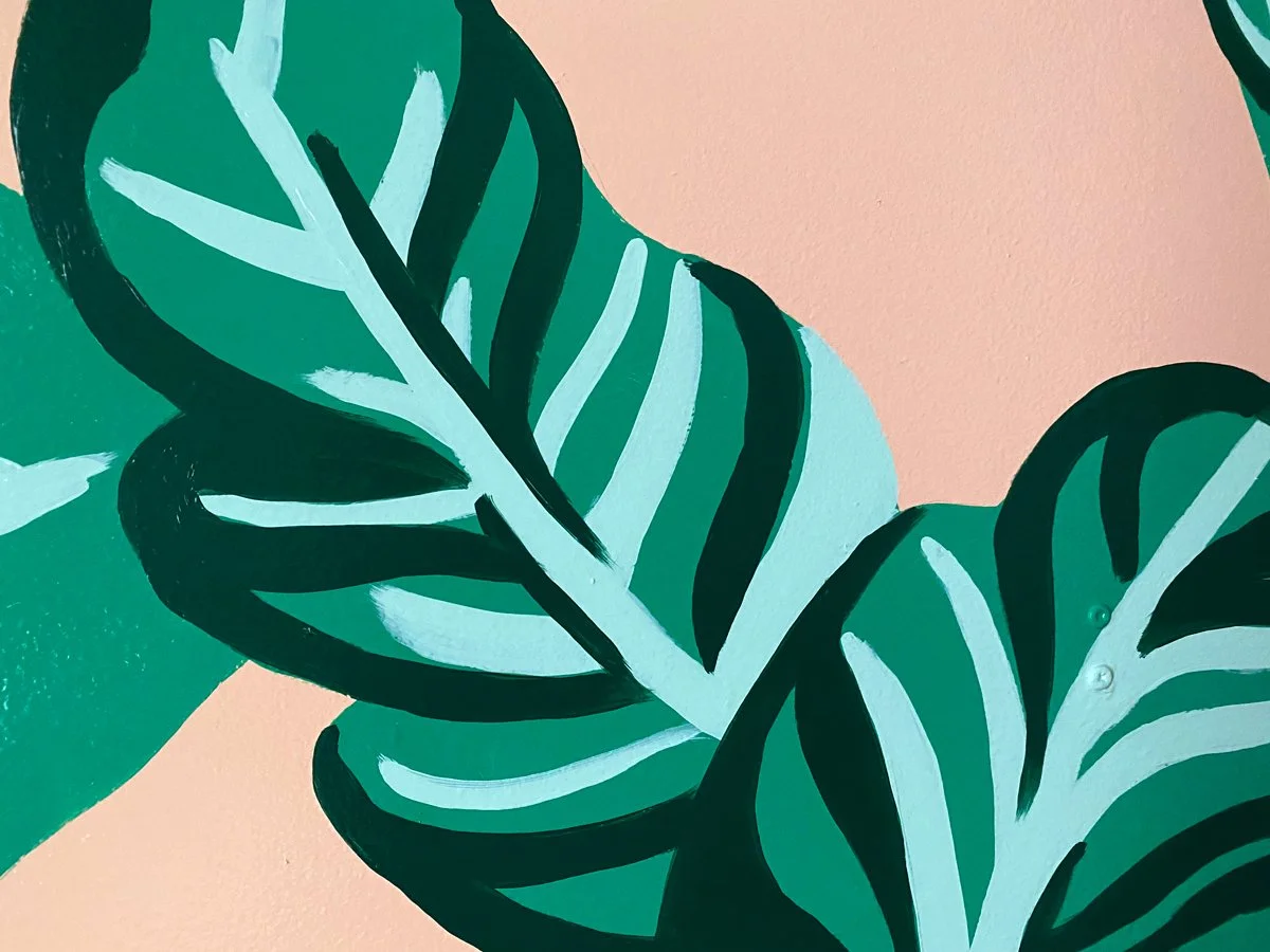 Tropical bathroom mural in Marquette Michigan with banana leaves on pink