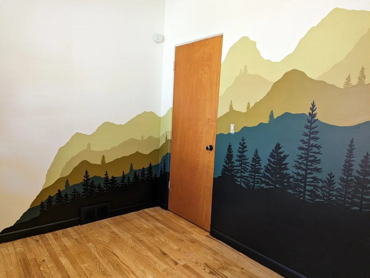 Mountain Bedroom mural painted in michigan with mountain layers and pine trees in green and gold.