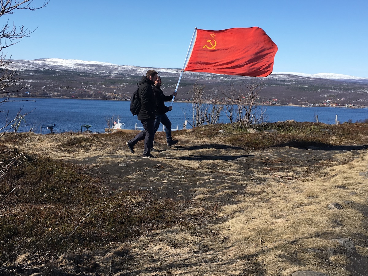 Two men carry a Soviet flag.