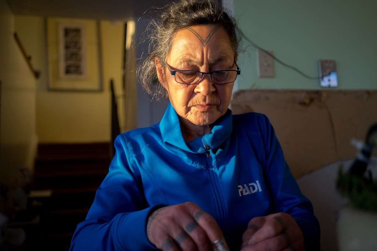 Aaju Peter sews a tie out of sealskin in her home.