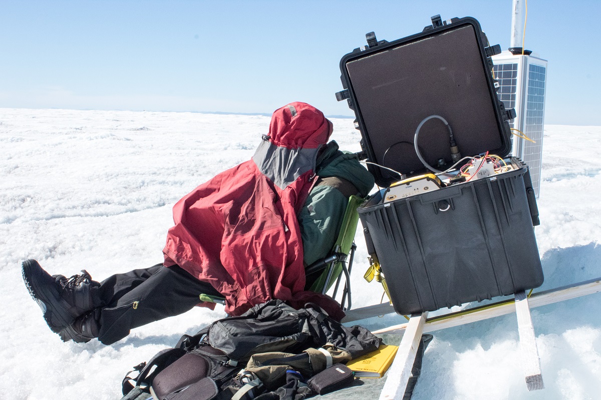 The 24-hour sunlight is so bright that researcher Toby Meierbachtol had to make a tent over his head in order to see the screen of a computer they're using to log the data from the ice sheet bed.