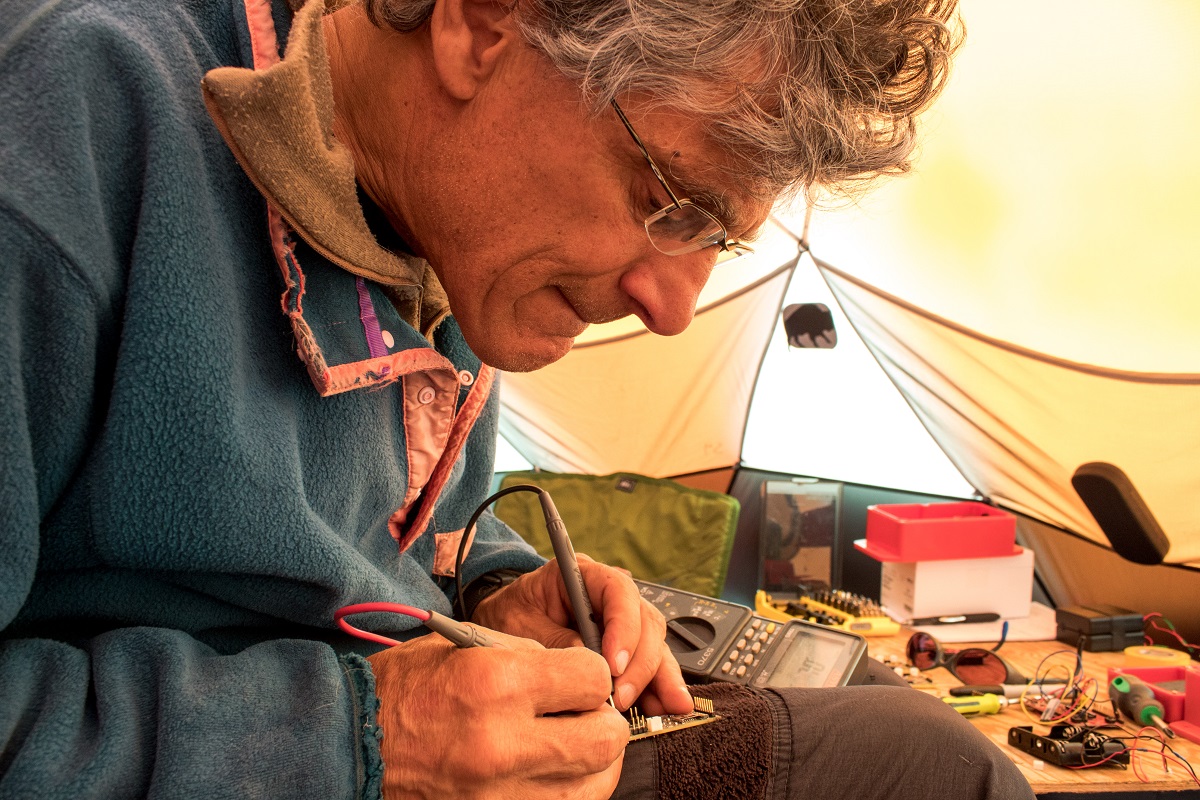 University of Wyoming glaciologist Neil Humphrey works on one of the tiny sensors the team sent down through a bore hole to collect information about the ice sheet bed.