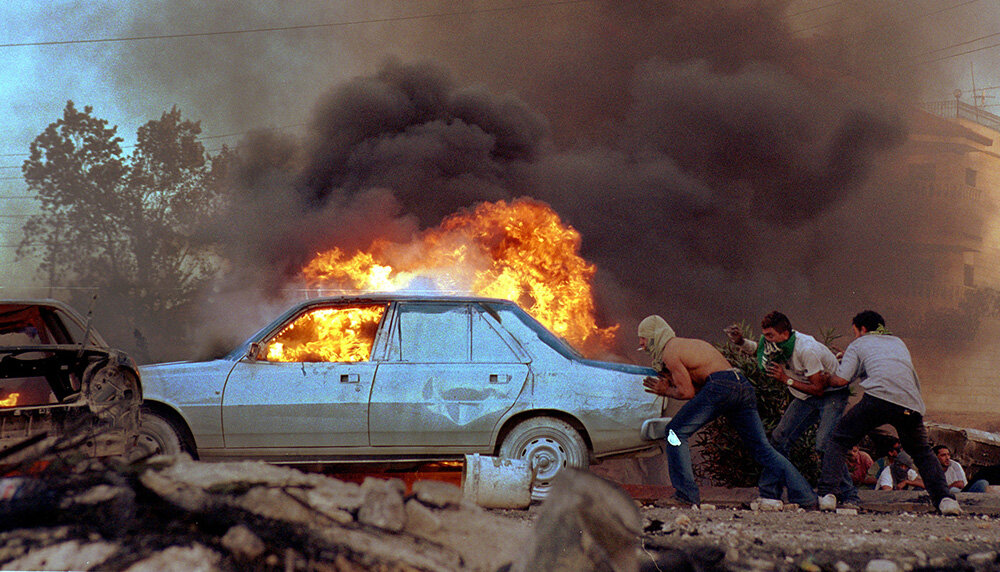 Three men pushing a burning car in Gaza in 2000. 