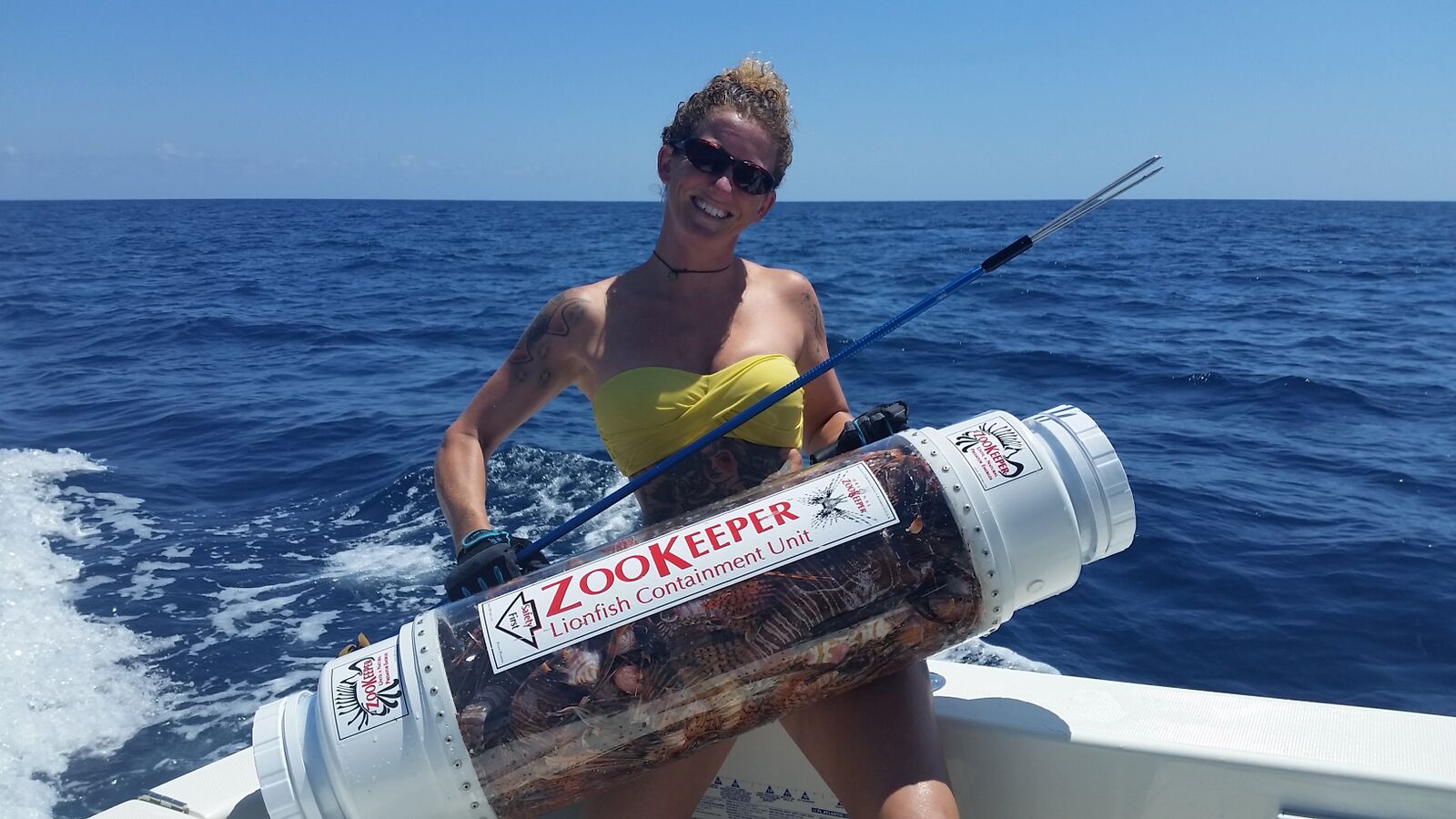 Rachel with her spear and zookeper, which holds the lionfish she catches and protects her from their venomous spines while she hunts. The gloves also protect her hands from the lionfish's spines.