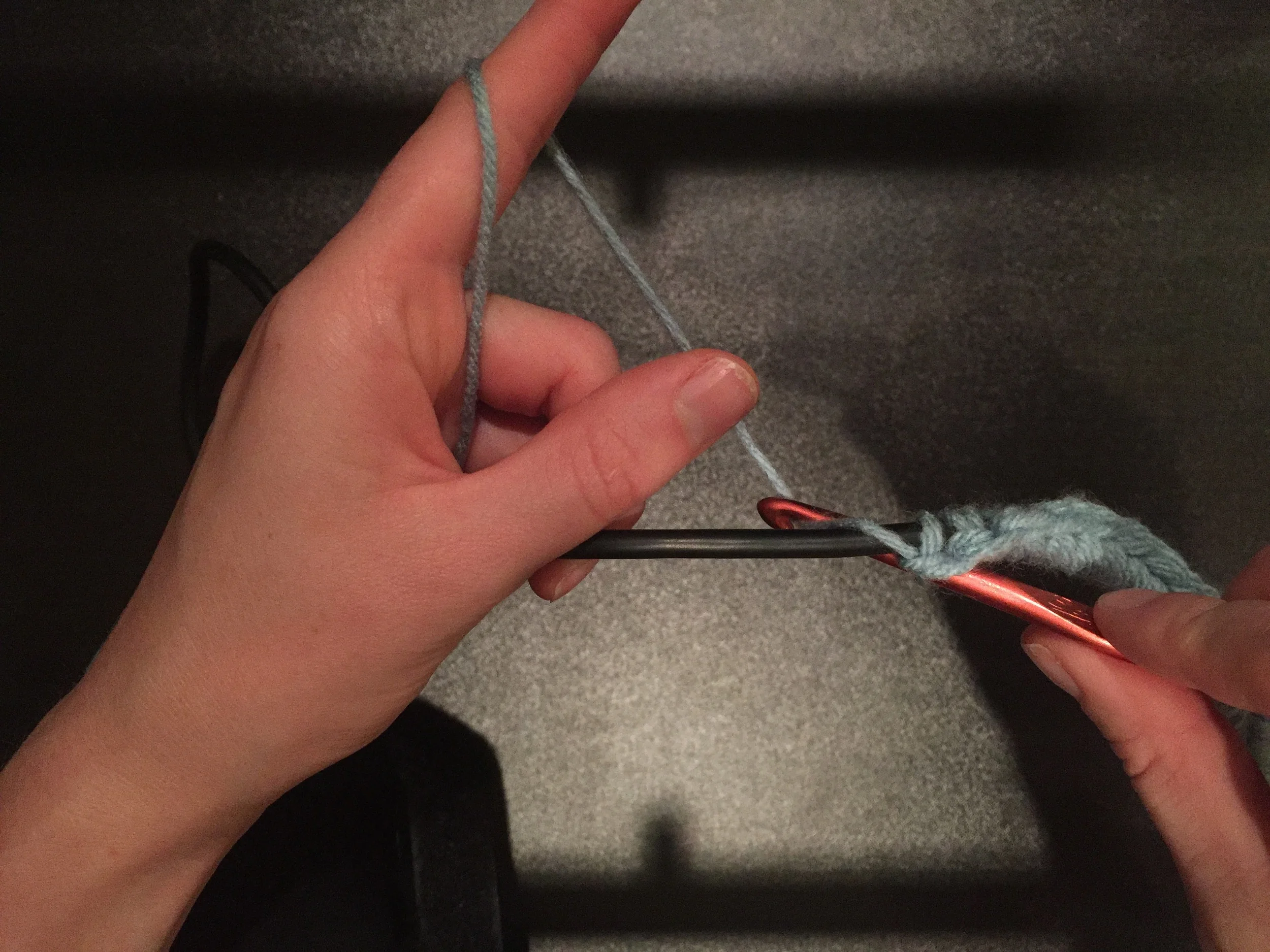 Take your crochet hook behind the cord and hook the yarn.