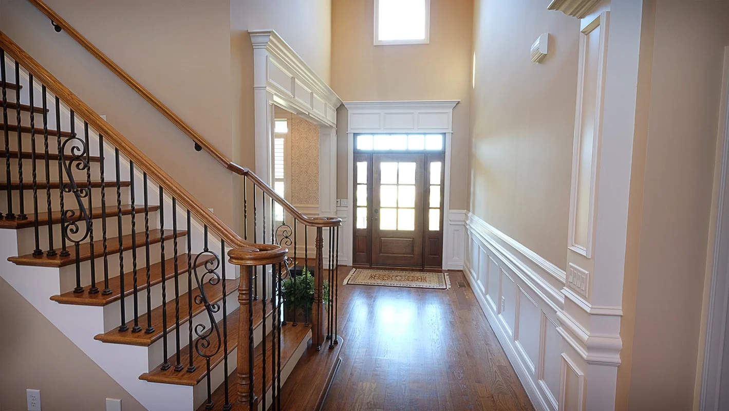Entry way with vaulted ceilings, white decorative wood trim, staircase and hardwood floors - Residential painting by Nash Painting Nashville TN