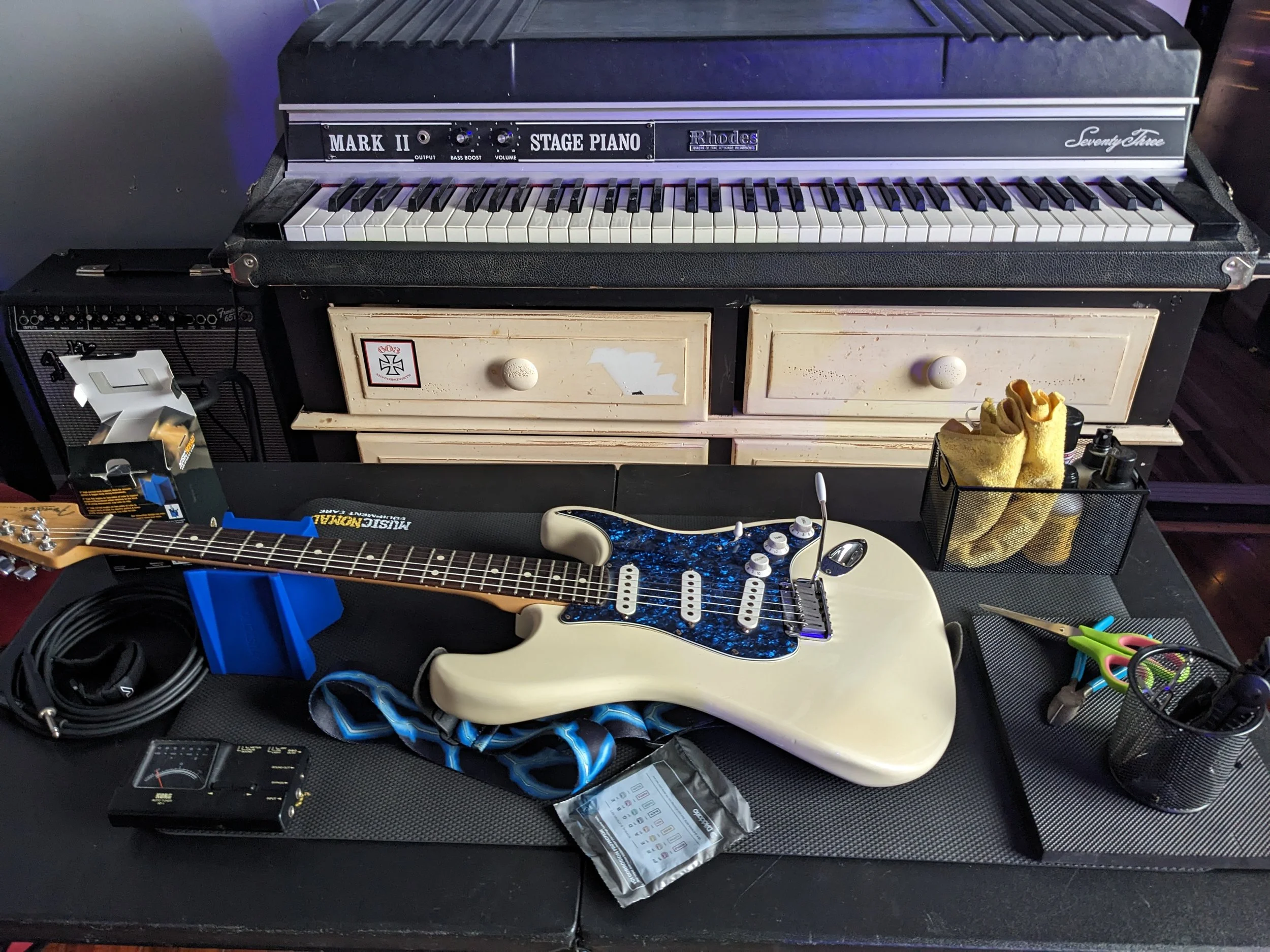 Close-up of a guitar being serviced for a professional restring and setup, showcasing the tools used for instrument maintenance in the Lakes Region.