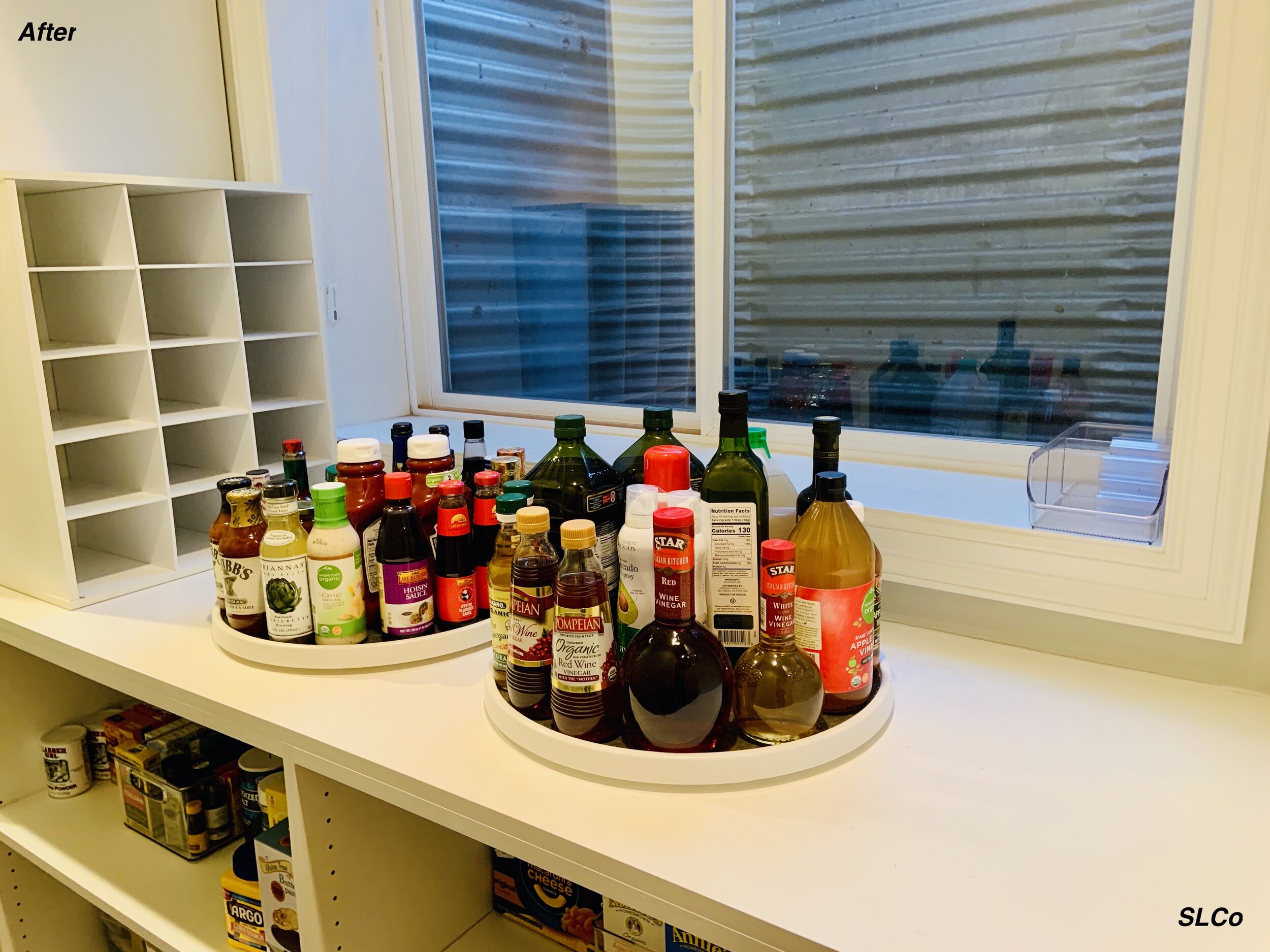 Large pantry counter with large lazy susans with oils on them and other items organized on shelves below.